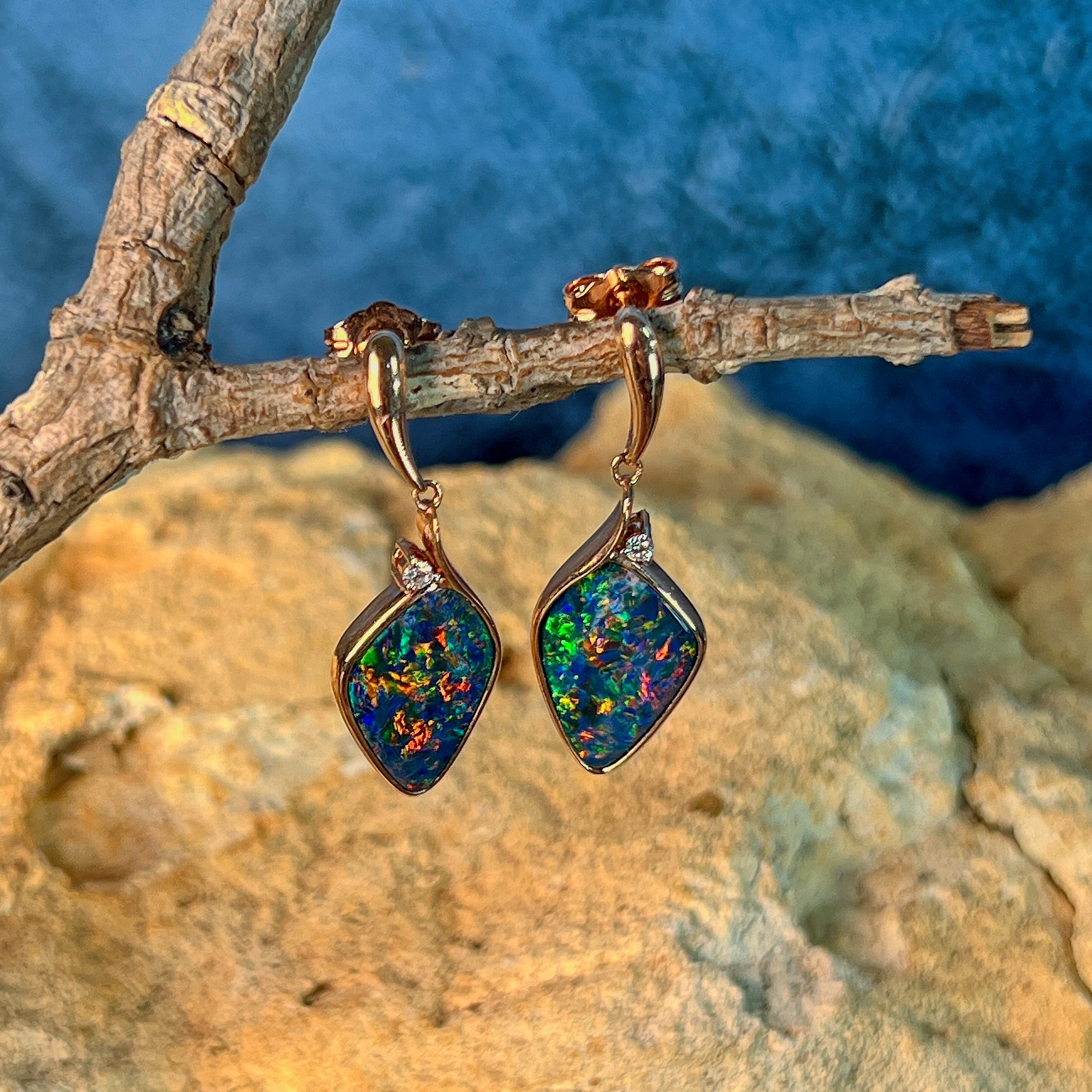 Kite-shaped opal doublet drops in 14kt rose gold resting against sandstone