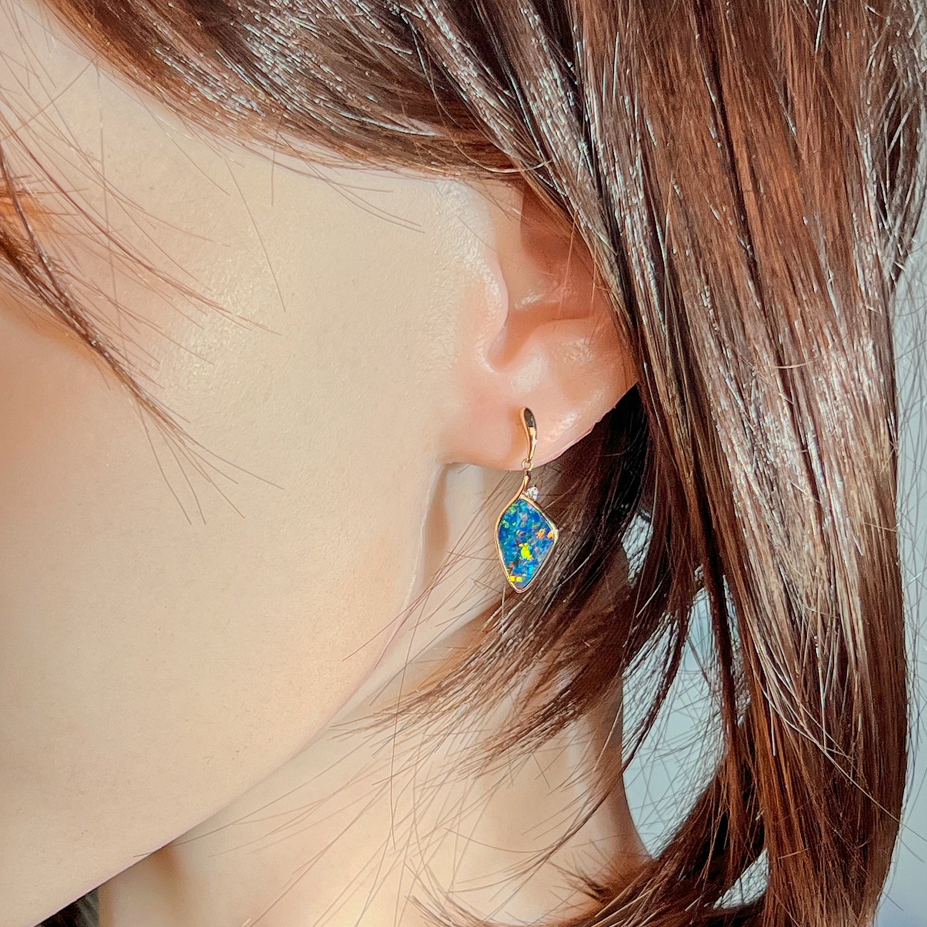 Multicolour opal doublet drop earring in rose gold worn on the ear beneath loose hair