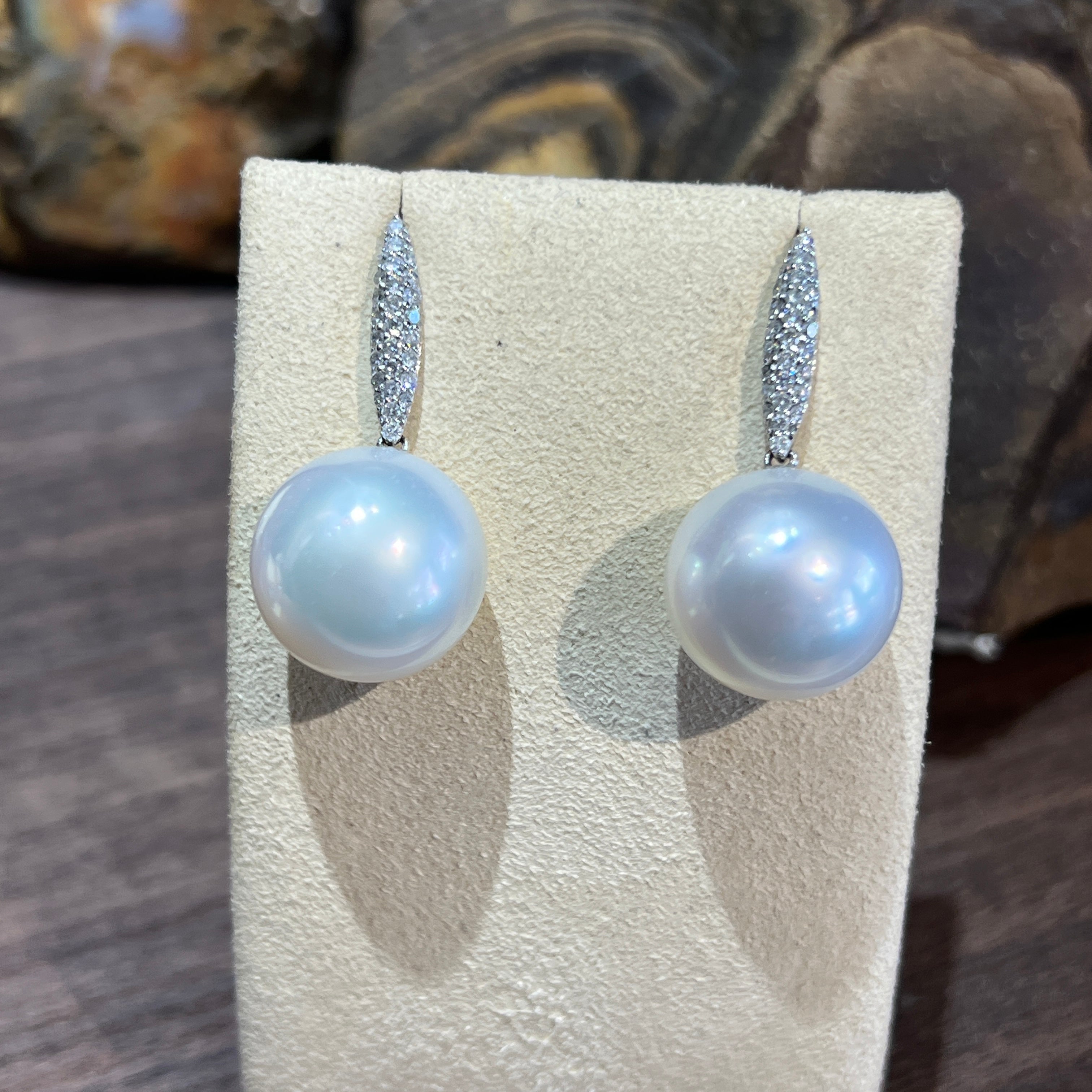 18kt white gold South Sea pearl and diamond drop earrings on a display stand, front view