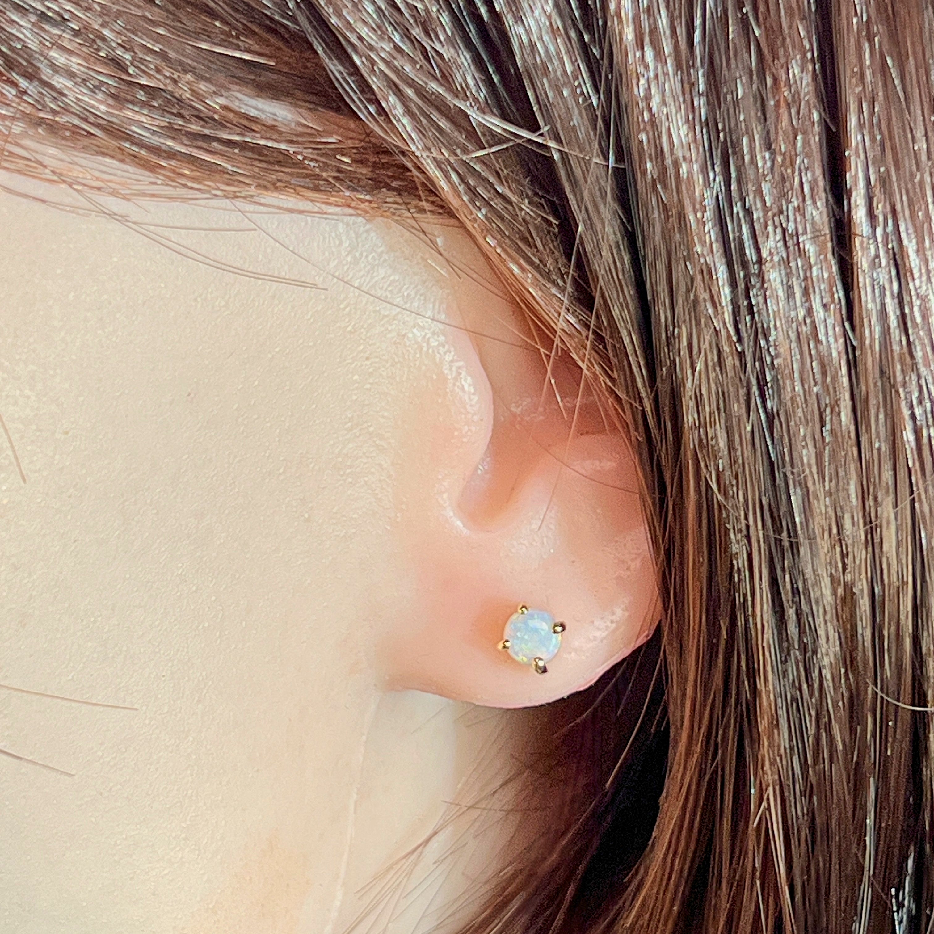 Round crystal opal stud earring worn in the ear