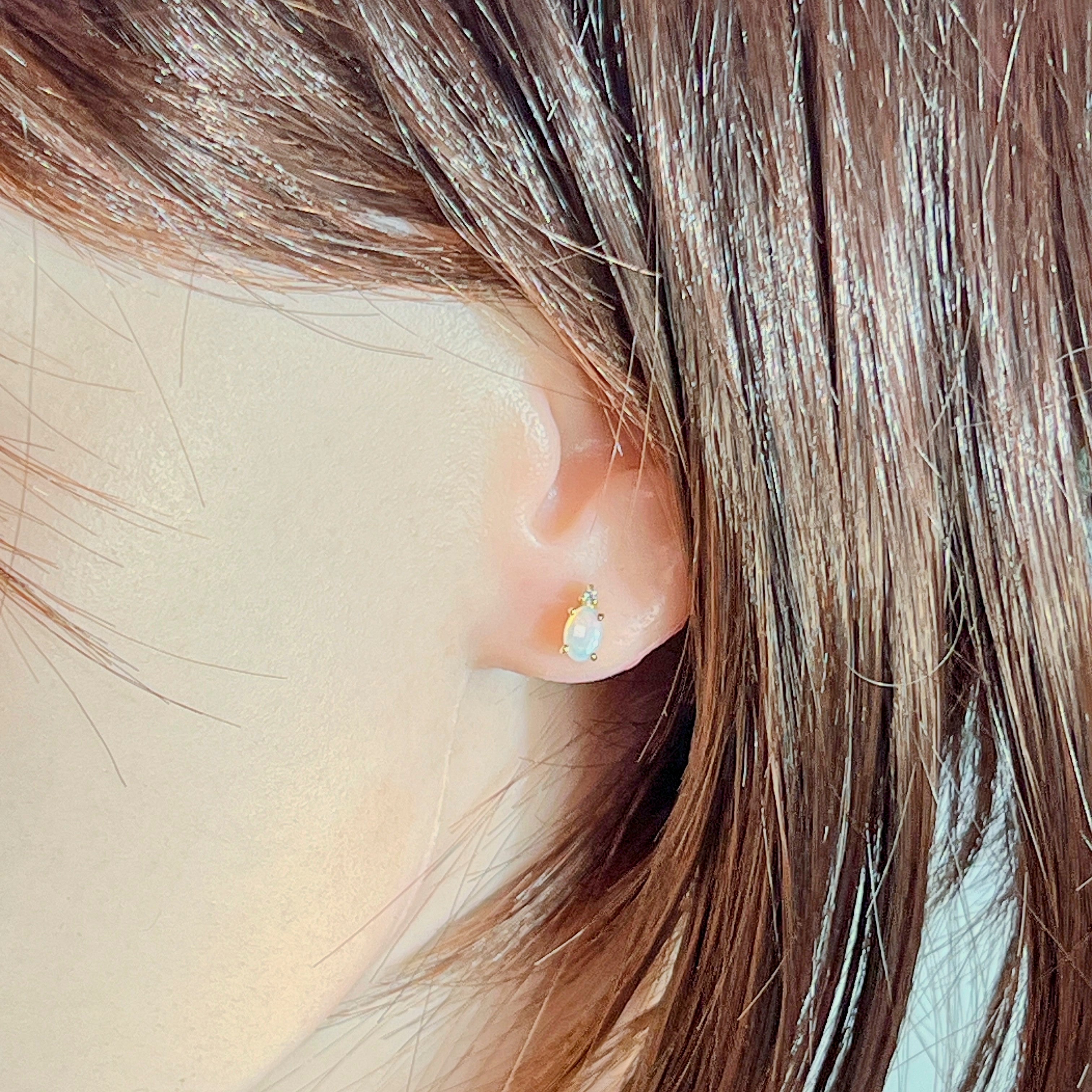 Worn view of the 6x4mm oval crystal opal stud with its diamond accent