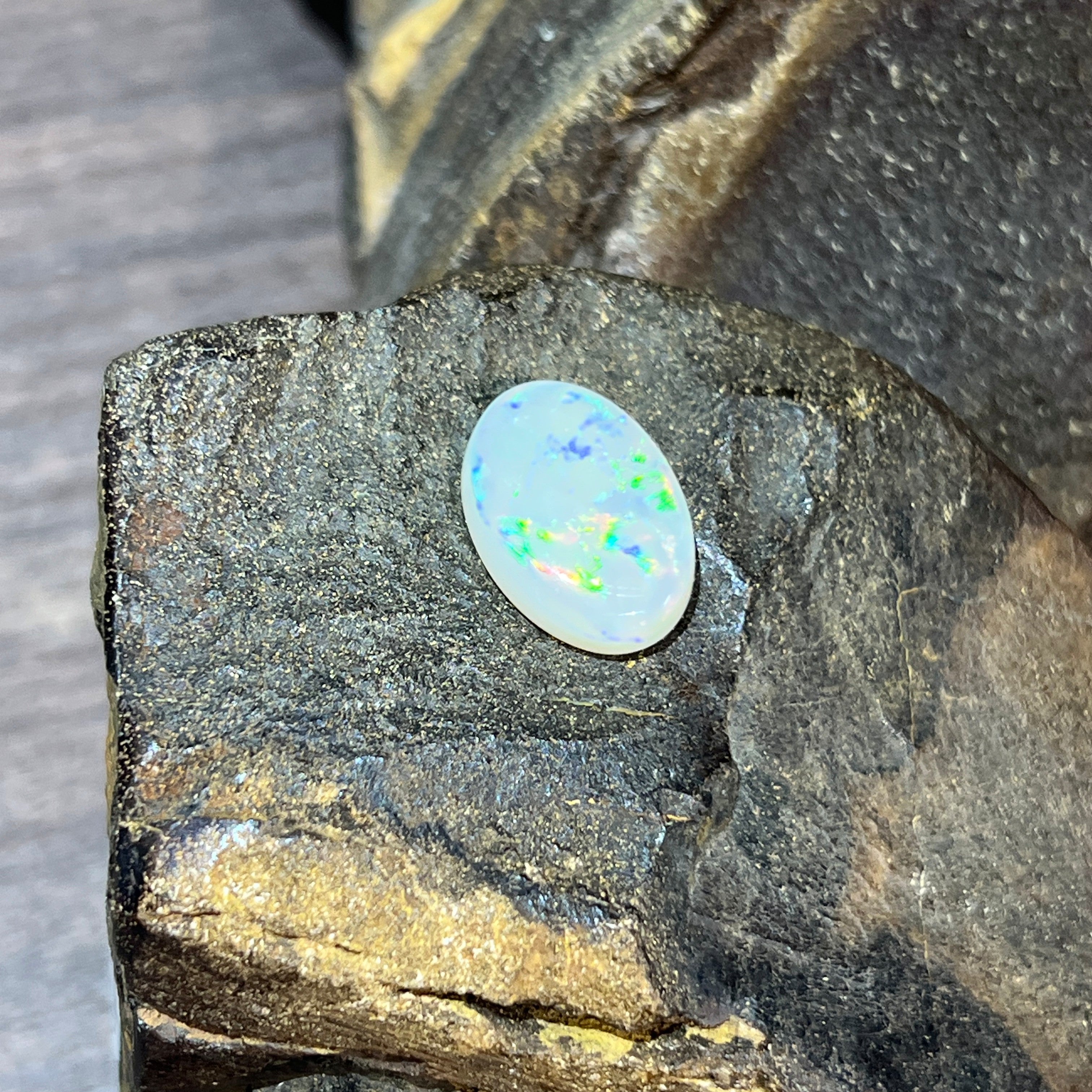 Upright view of the 5.56ct white opal showing green pinfire across its face