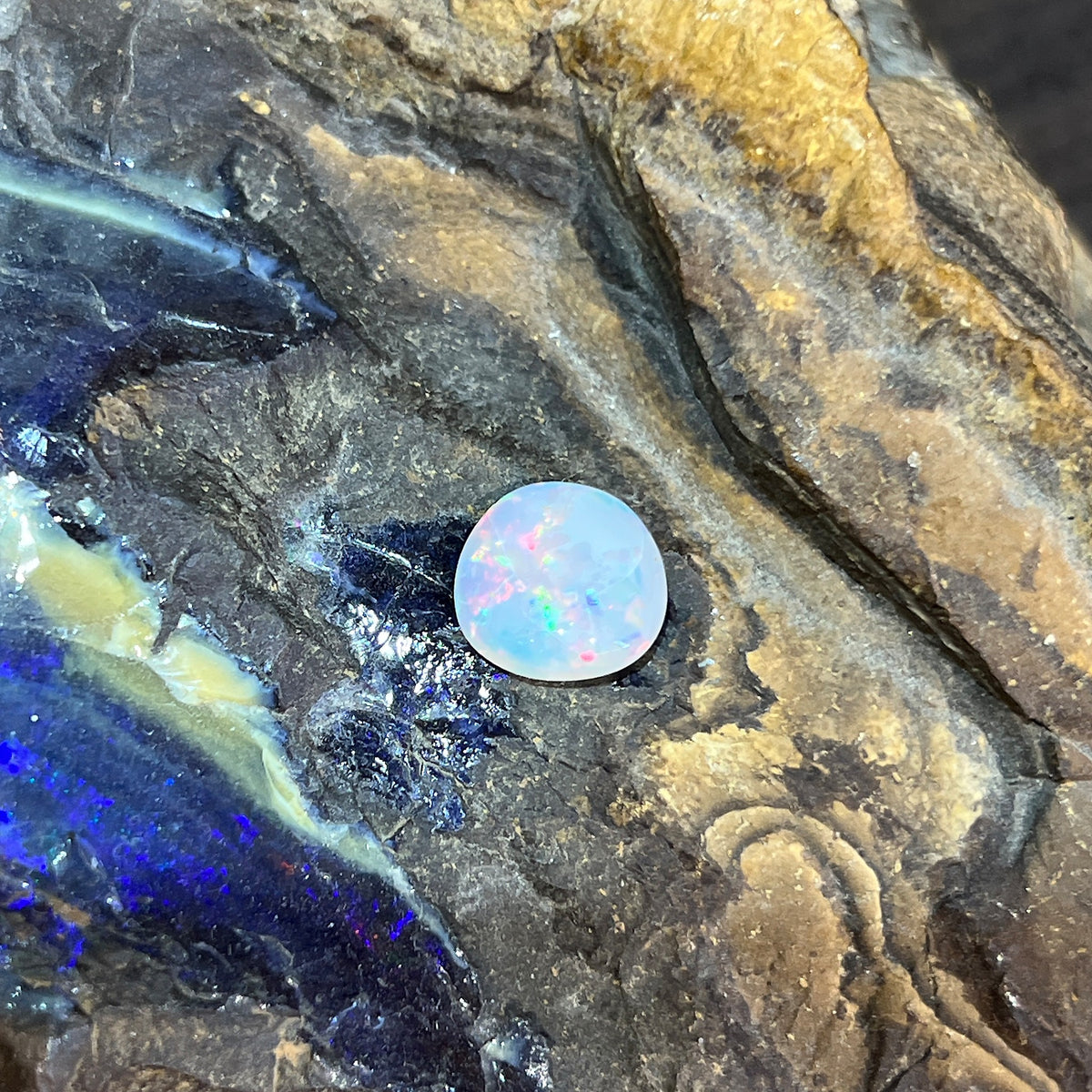 3.60ct freeform white opal loose stone, blue, green and red play-of-colour, unset, on rock