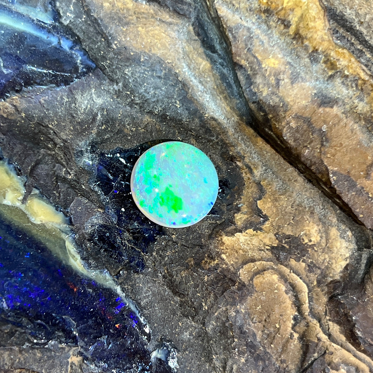 3.25ct round crystal opal loose stone, yellow and green play-of-colour with a hint of blue, unset, on rock