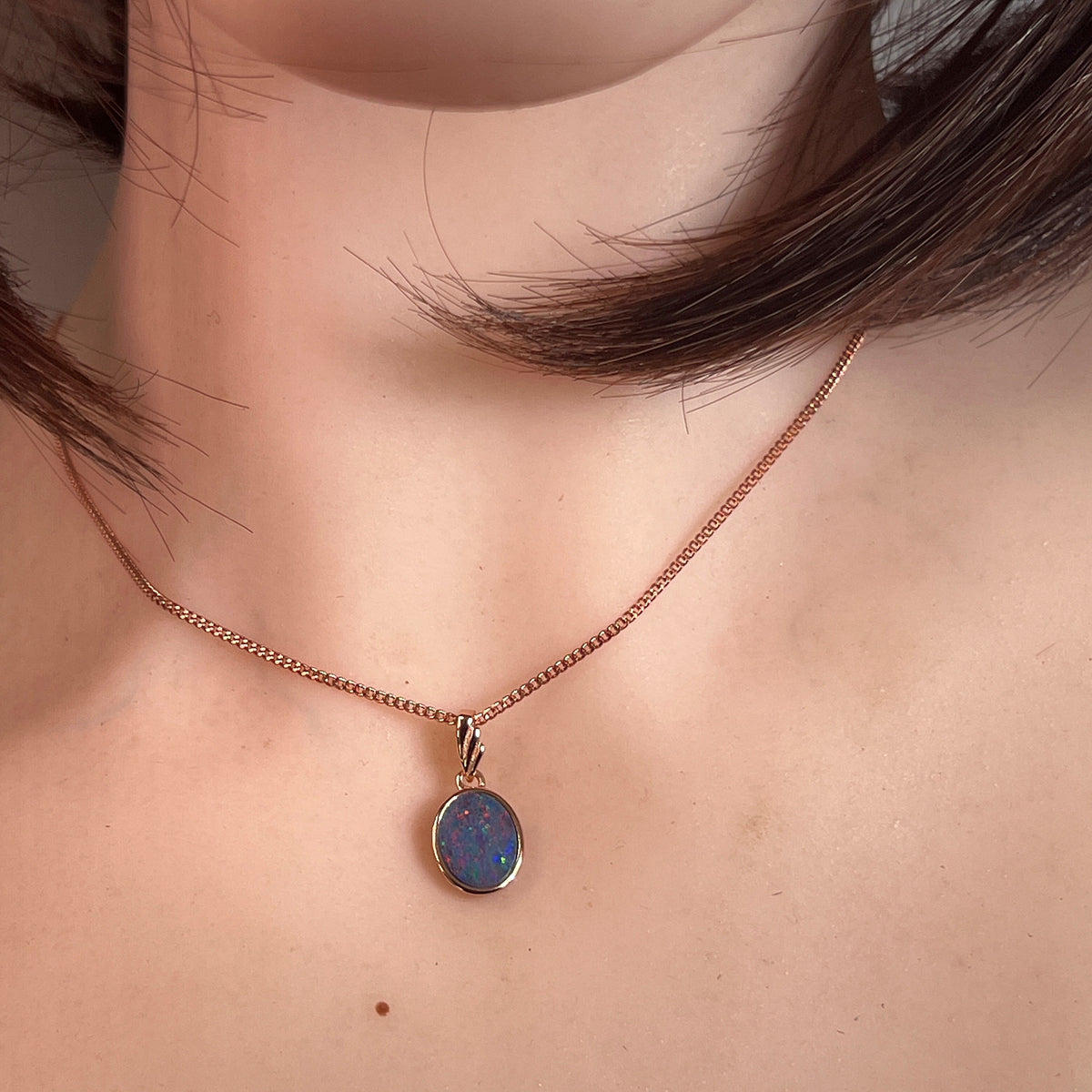 Australian opal doublet pendant worn at the neck, red, blue, green and violet play-of-colour