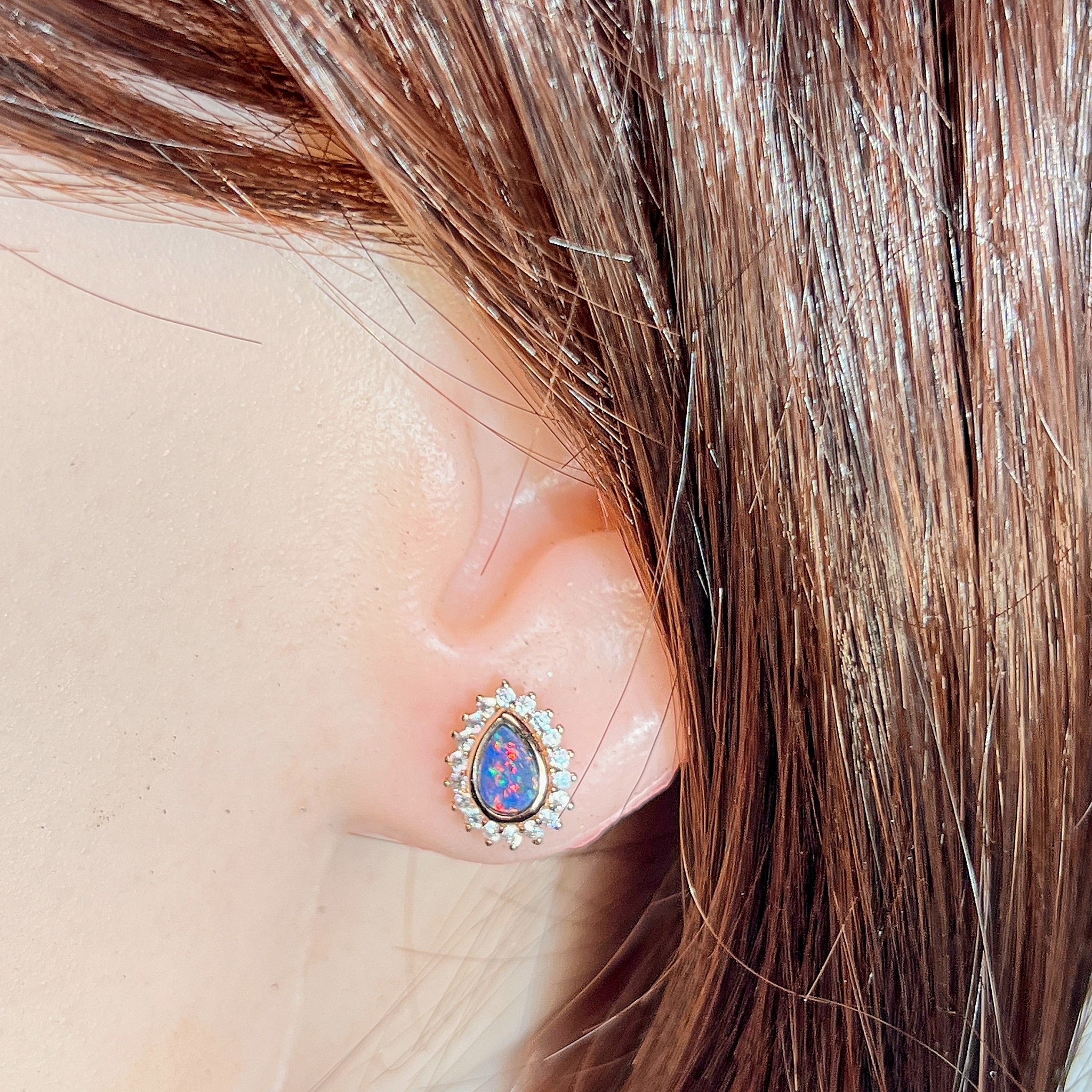 Australian opal doublet earrings worn on the ear, red, blue and green play-of-colour