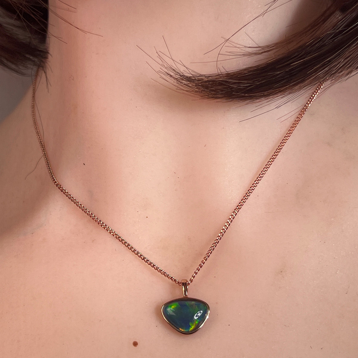 Australian opal triplet pendant worn at the neck, red, blue, green and yellow play-of-colour