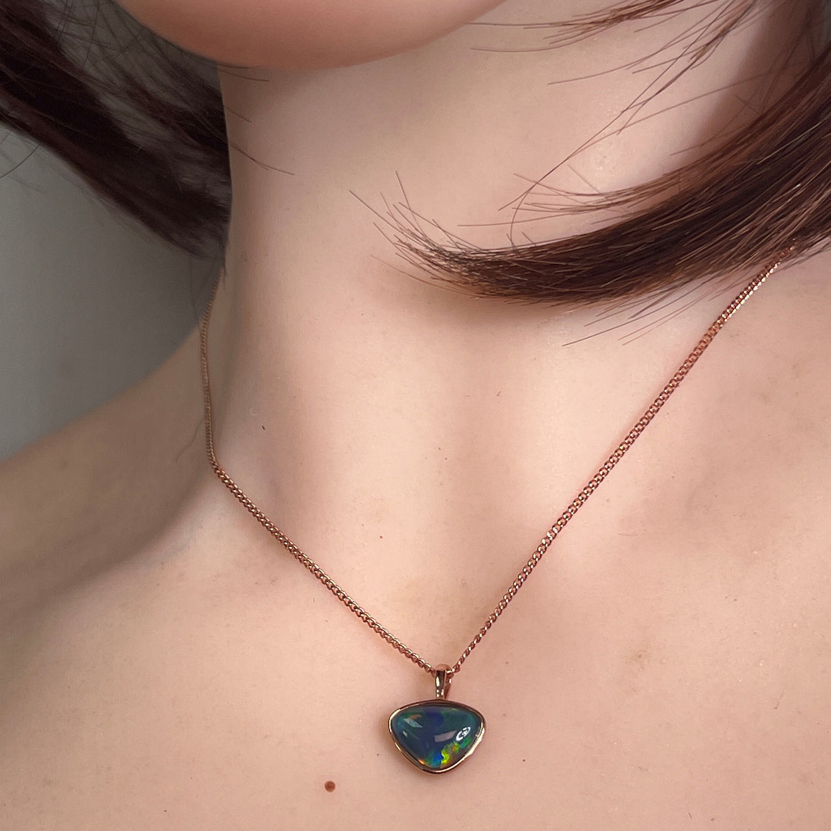 9 x 11mm freeform Australian opal triplet pendant worn at the neck, rose gold-plated silver