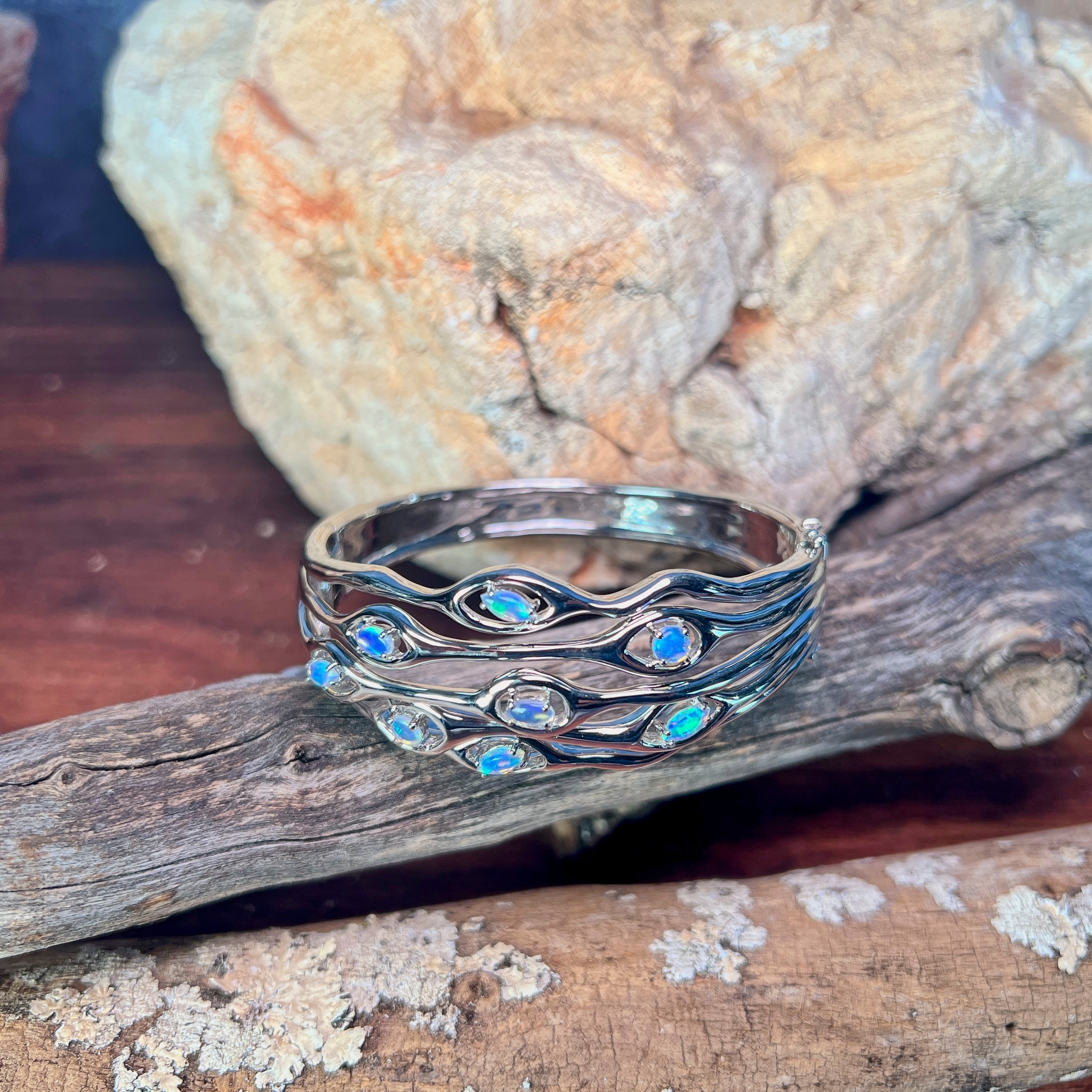Australian opal set into the wave cut-out band of a sterling silver bangle