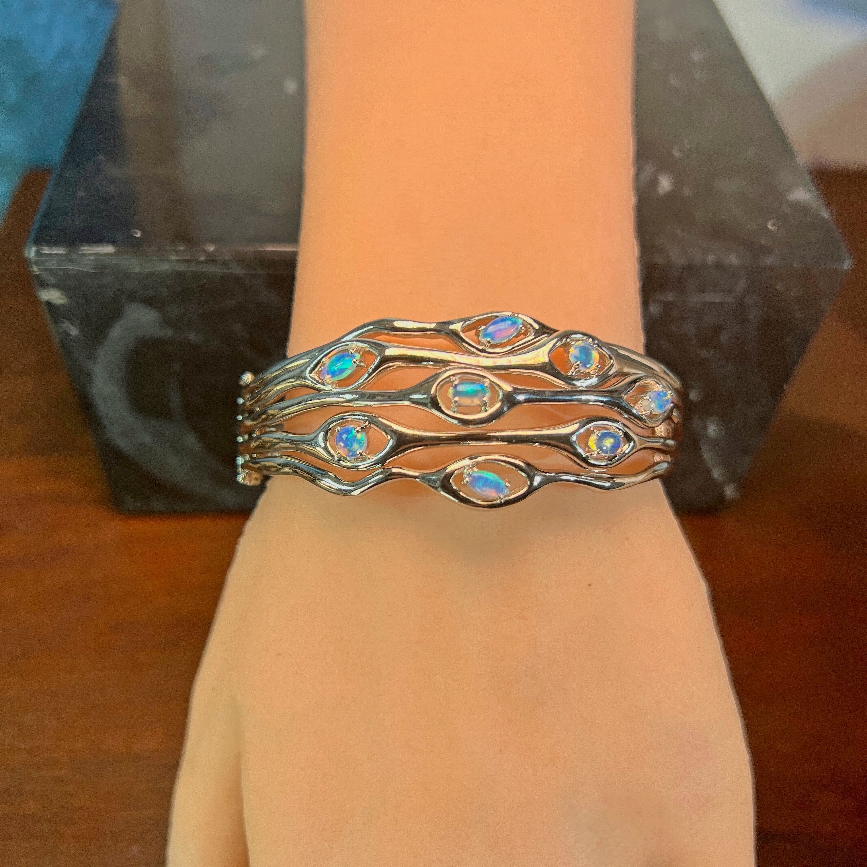 Sterling silver opal wave bangle worn on the wrist
