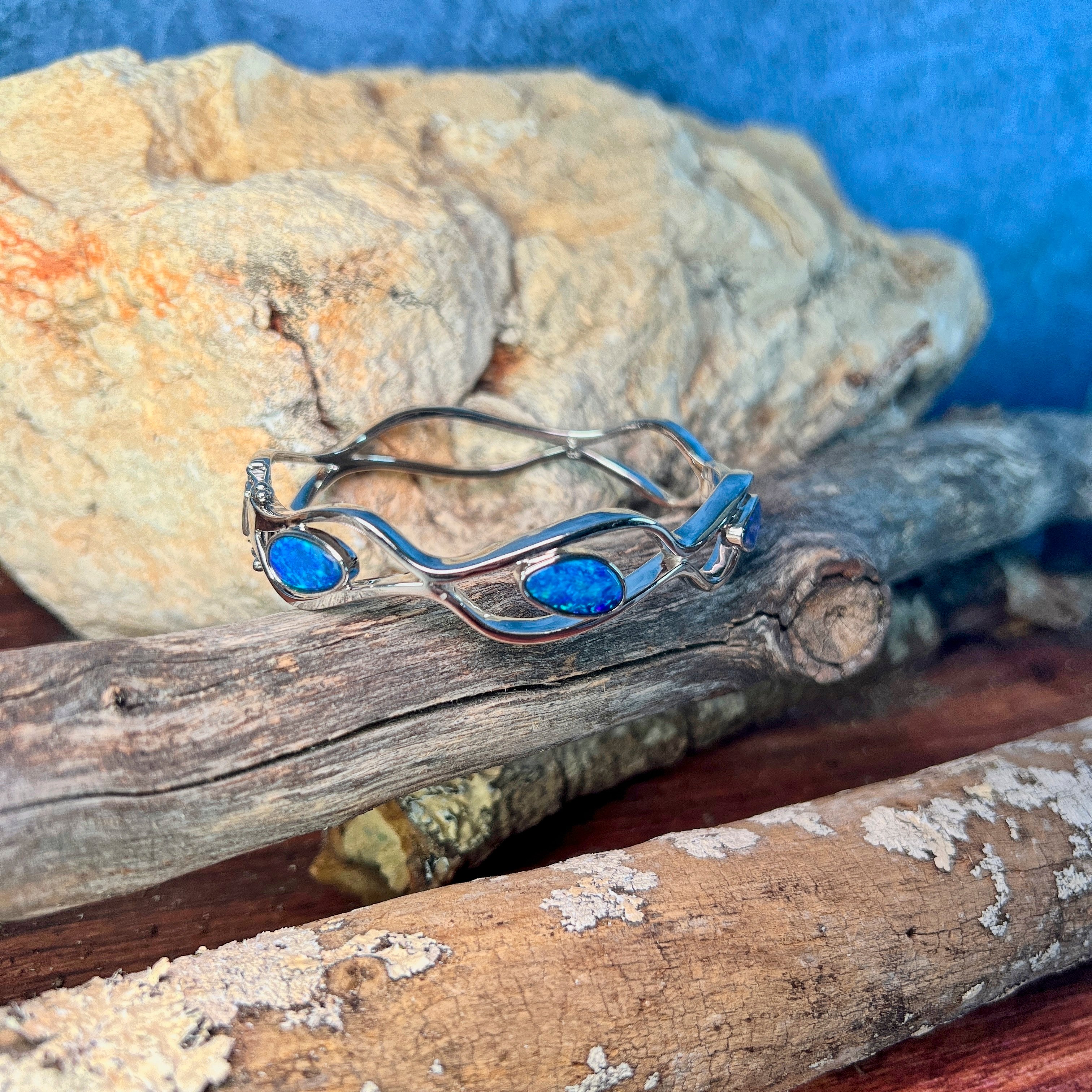 Freeform Australian opal doublet in a sterling silver wave bangle, showing green and blue flash