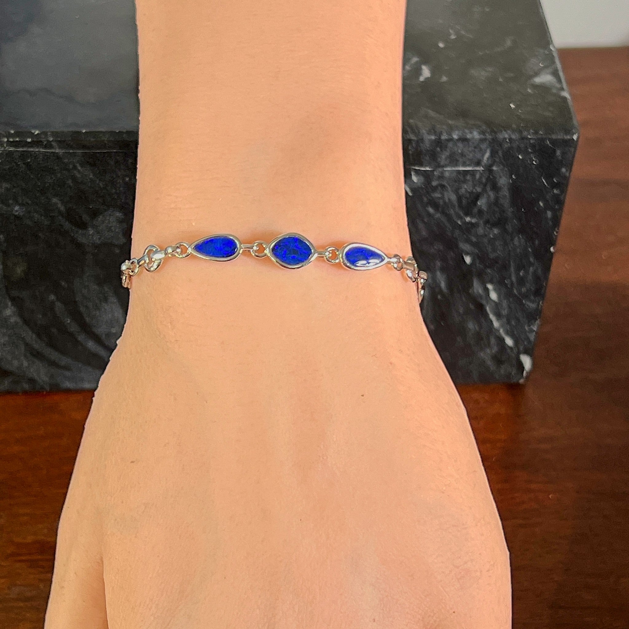 Sterling silver bracelet with three opal doublets worn on the wrist, full view of the linked stones
