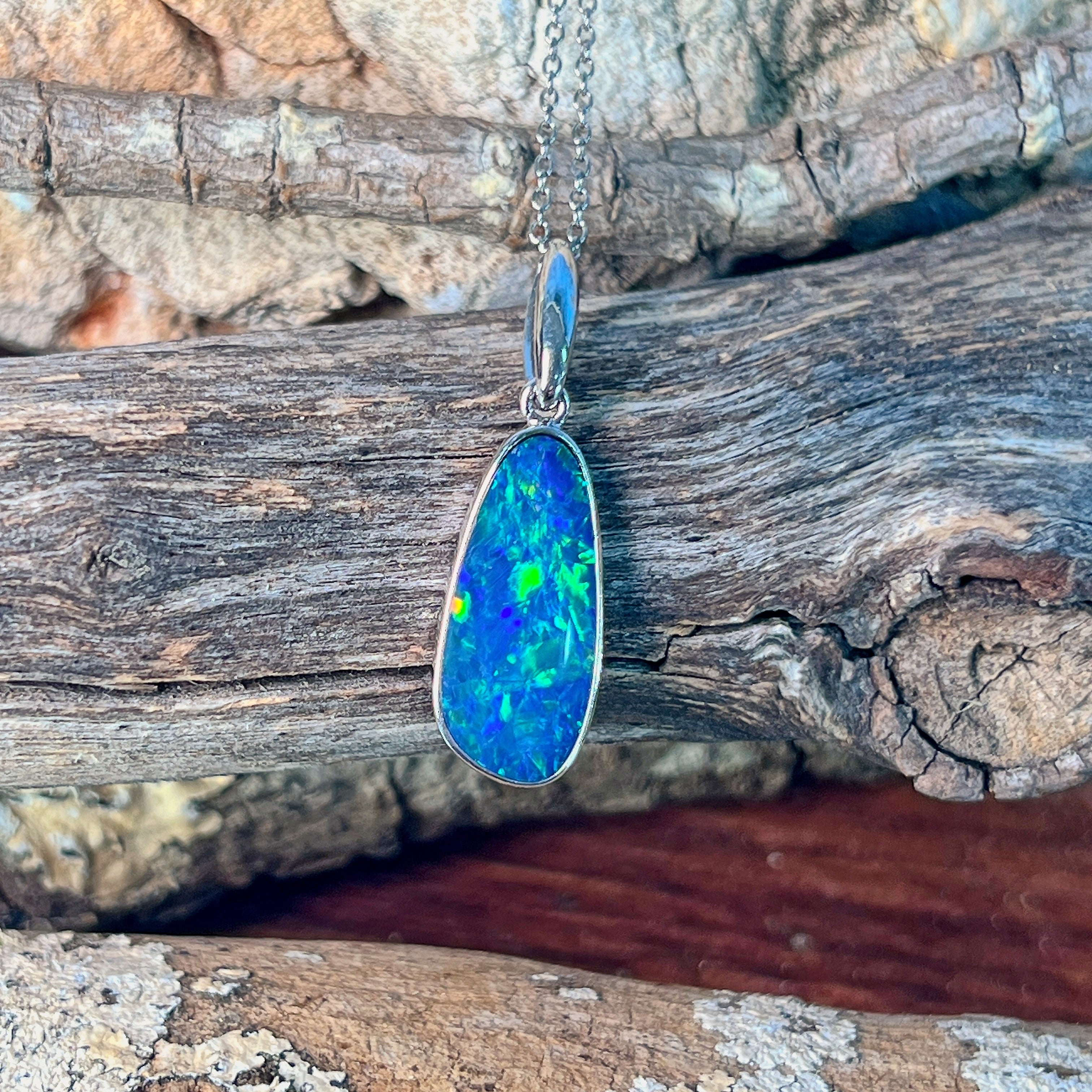 Blue-green opal doublet pendant in sterling silver angled to catch the light