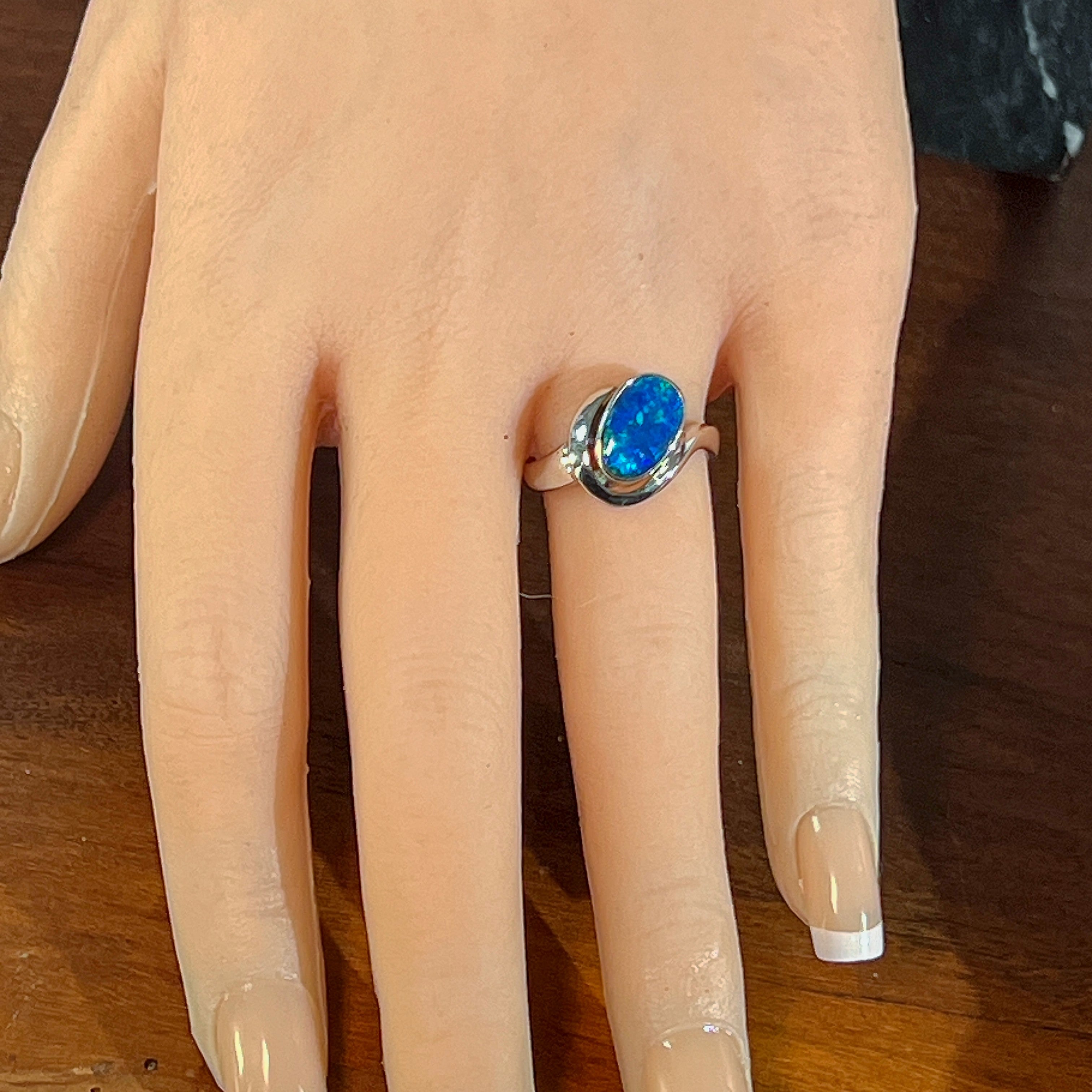 Deep blue opal doublet ring in silver worn on the hand, viewed across the fingers