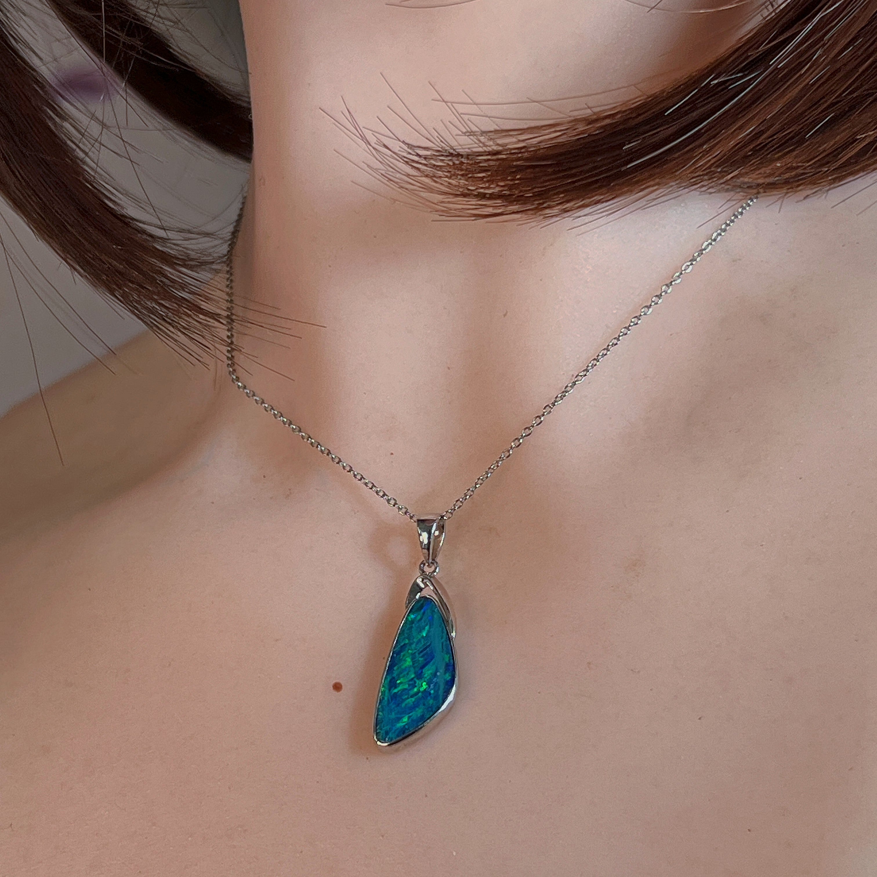 Wing-shaped opal doublet pendant worn at the neck, close view on the chain