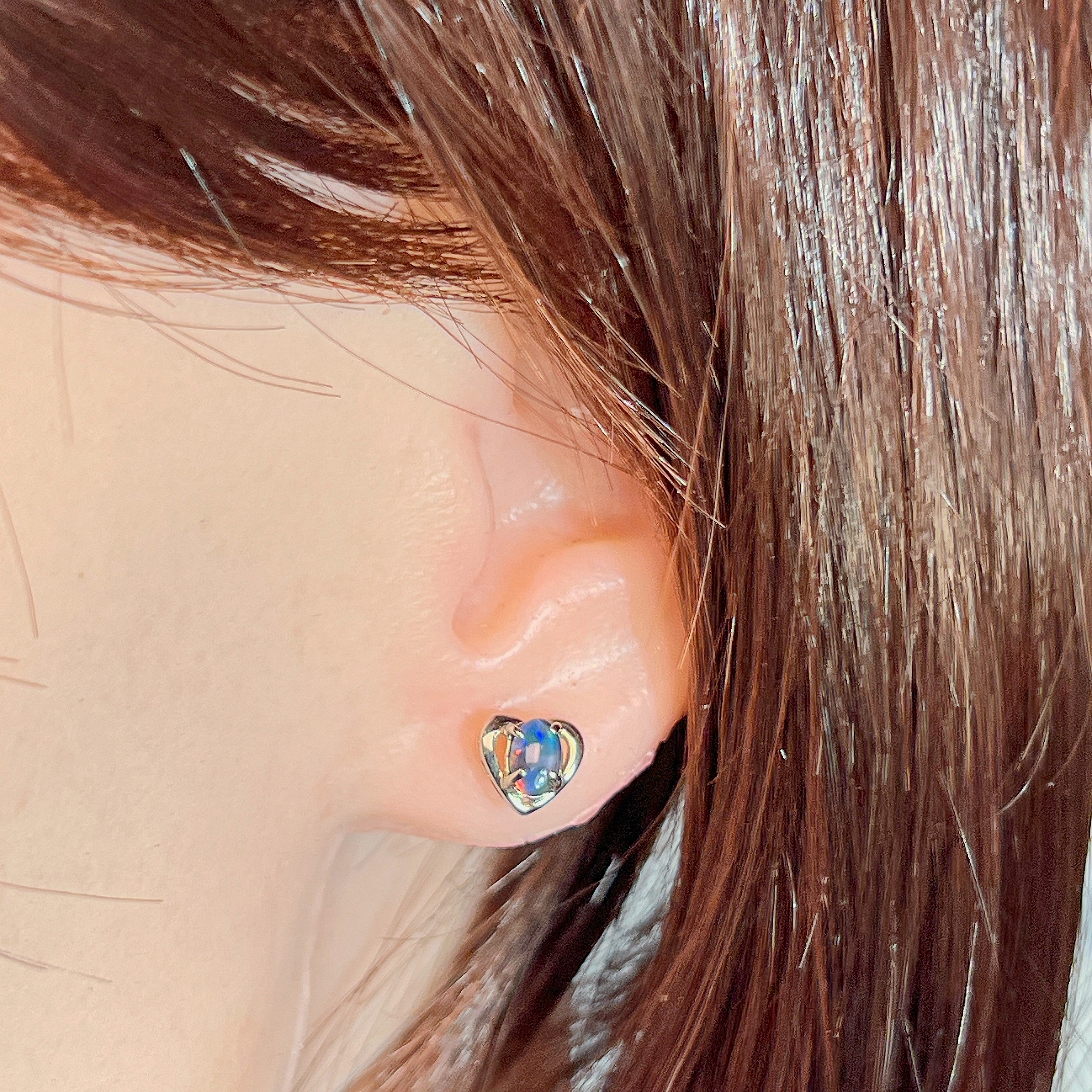 Heart-shaped opal triplet stud earring worn on the ear, showing its scale on the earlobe