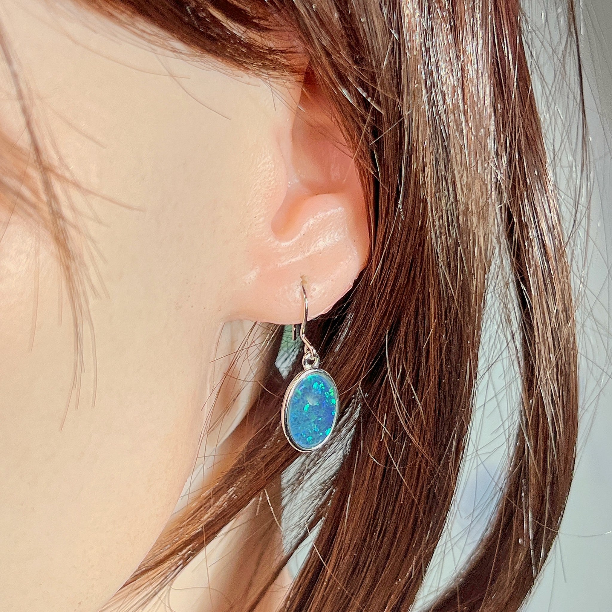 Australian opal triplet earrings worn on the ear, blue and green play-of-colour