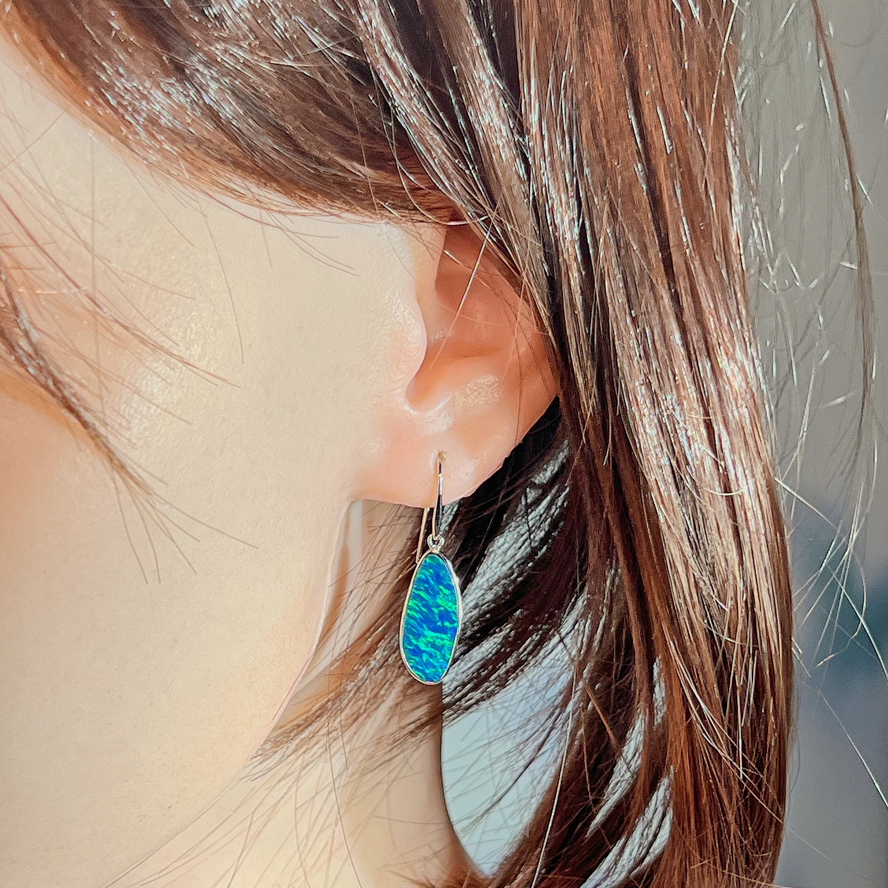 Freeform opal doublet drop earring in white gold worn on the ear, side profile view