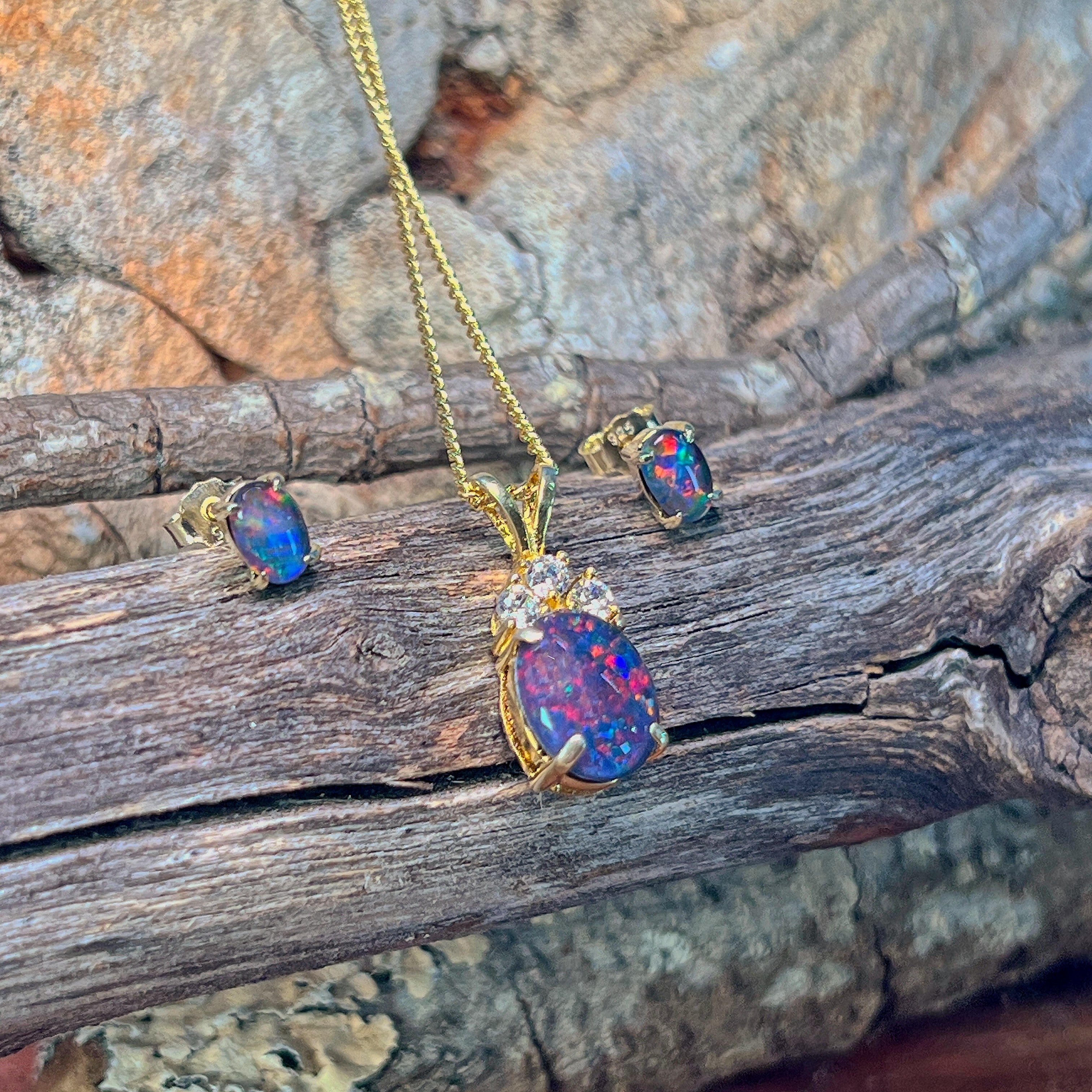 Opal triplet pendant and 6x4mm studs in gold-plated silver against driftwood and stone
