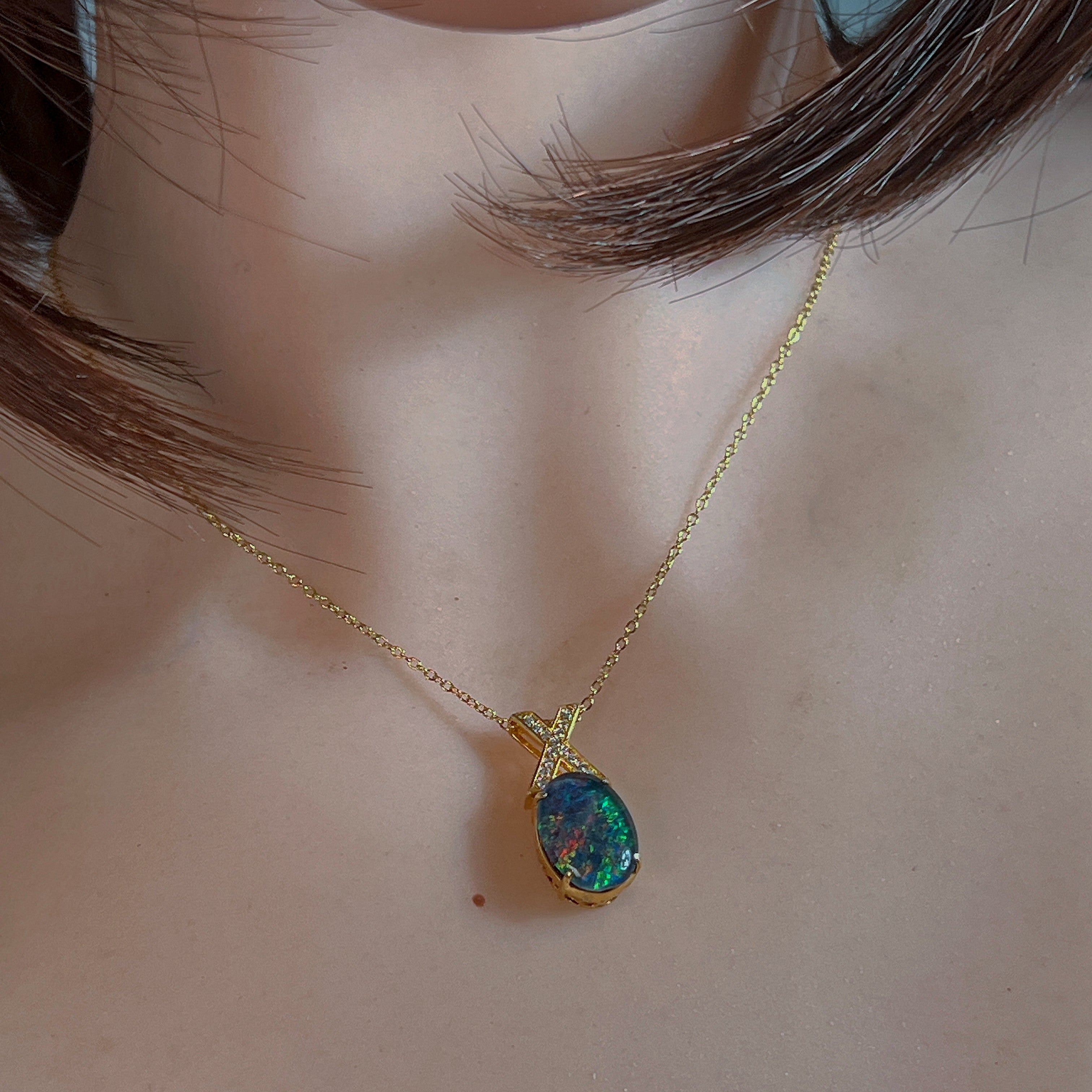 Oval opal triplet pendant with X-shaped bail worn at the neck, close view