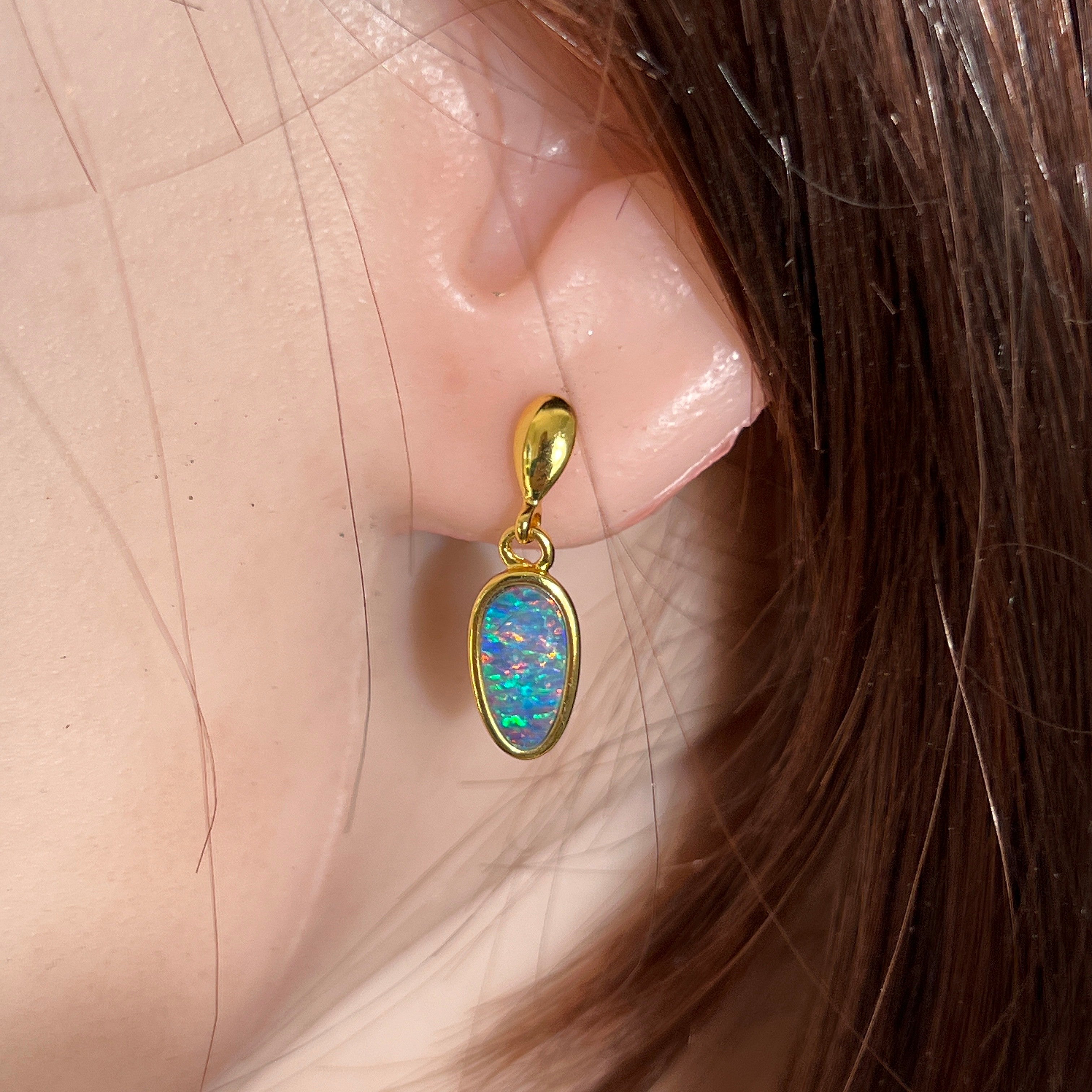 11 x 6mm pear-shaped Australian opal doublet earrings worn on the ear, yellow gold-plated silver