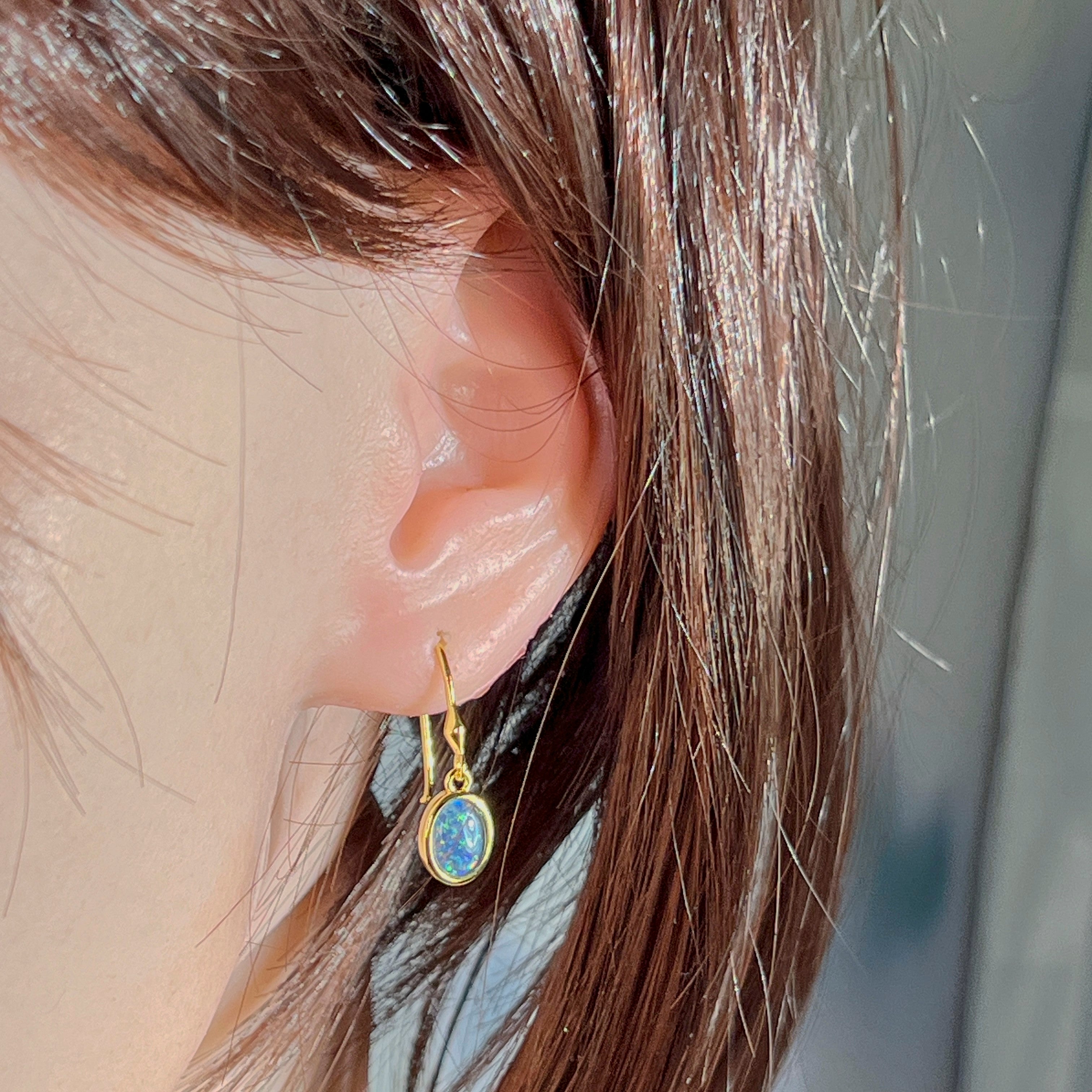 Worn close-up of the 8x6mm oval opal triplet earring in yellow gold plated sterling silver