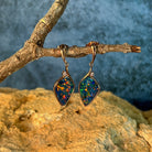 Rose gold opal doublet drop earrings hanging from a branch above sandstone