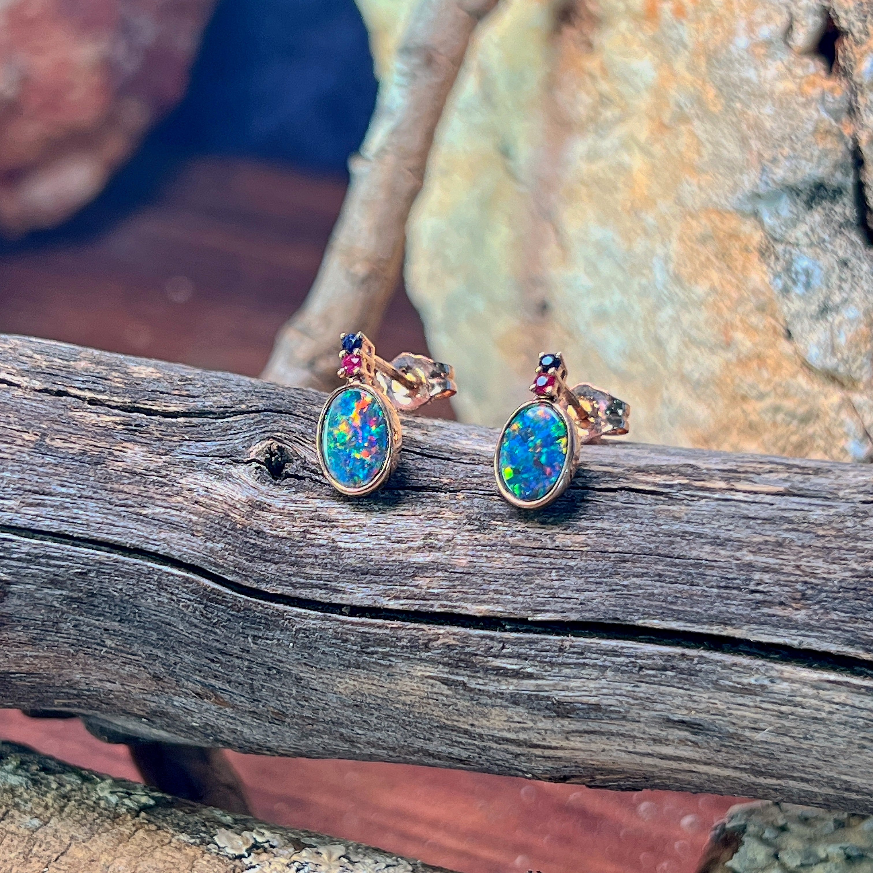 14kt rose gold opal doublet stud earrings showing blue and pink flash across the ovals