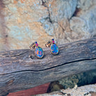 Oval opal doublet studs in rose gold with gemstone accents, angled on driftwood