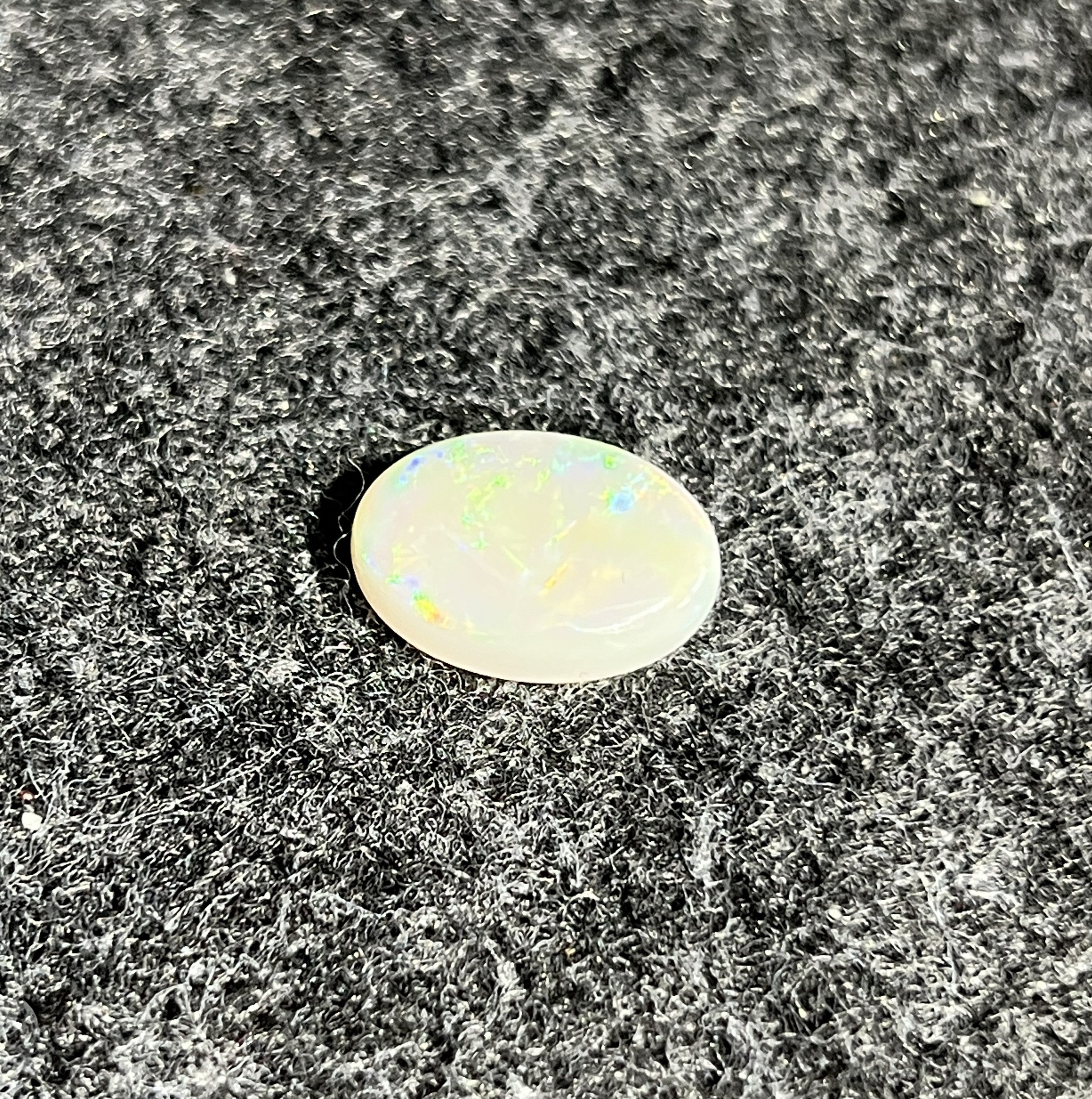 Natural Australian white opal, 5.56ct oval cabochon 16x12mm, showing green play-of-colour