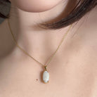 White opal pendant worn close up, oval Australian white opal in 18kt yellow gold