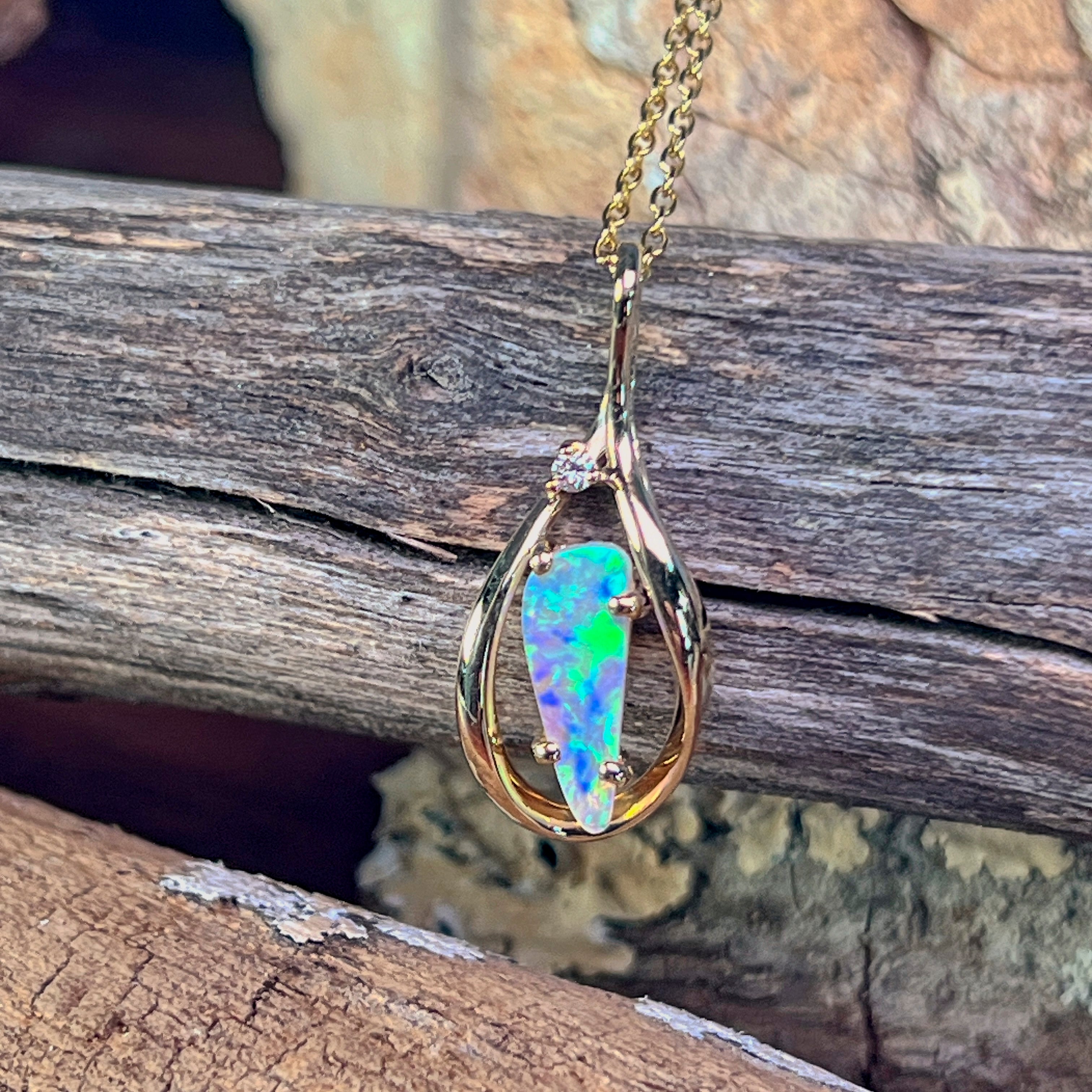 Crystal opal pendant showing green and pink play-of-colour against the gold frame