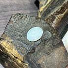 16x12mm oval white opal with pale blue and green flashes across the dome