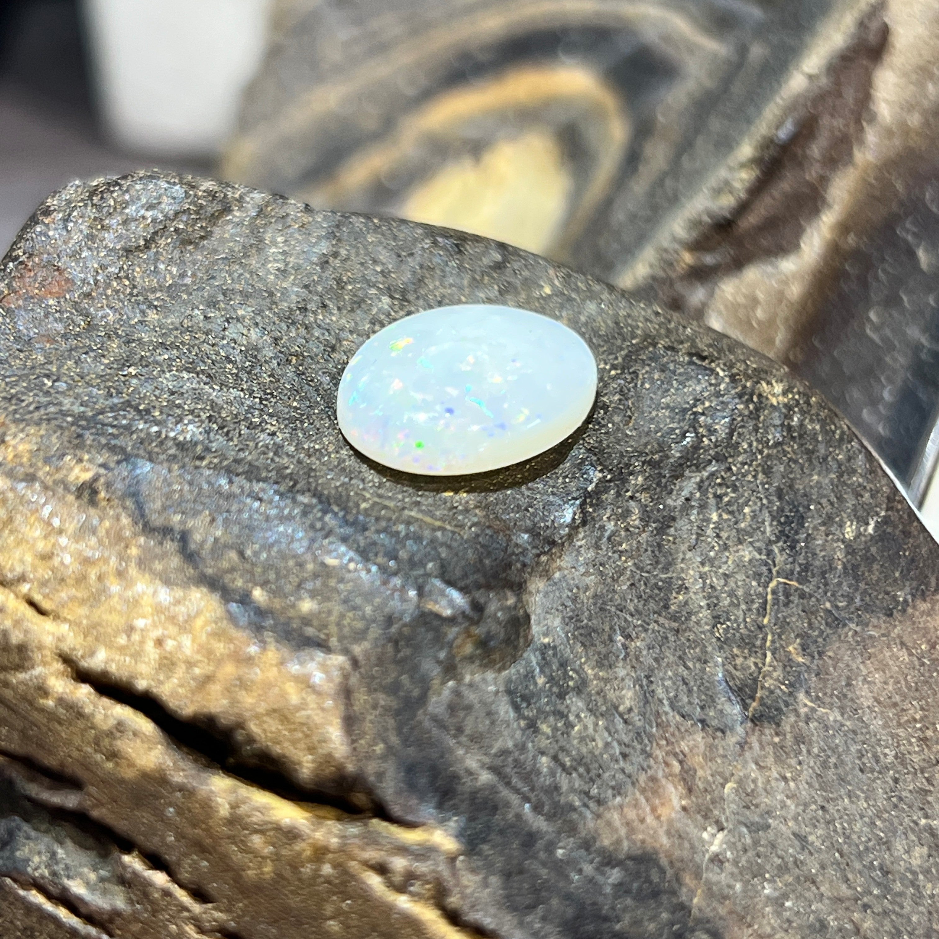 4.89ct white opal cabochon angled to show green and blue pinfire play-of-colour