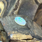 Angled view of the 5.56ct white opal, green sparkle scattered across the dome