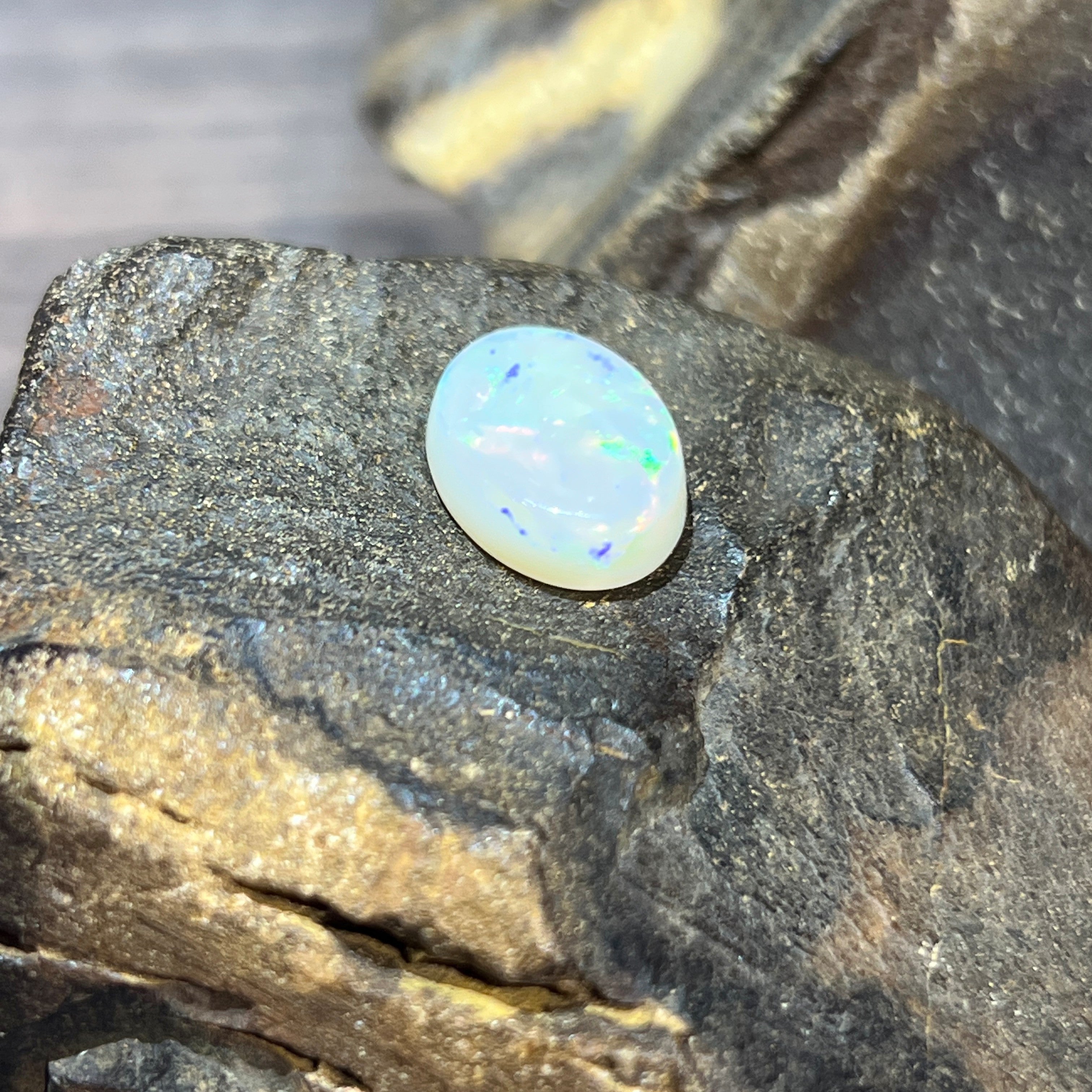 16x12mm oval white opal with soft blue-green shimmer under diffused light