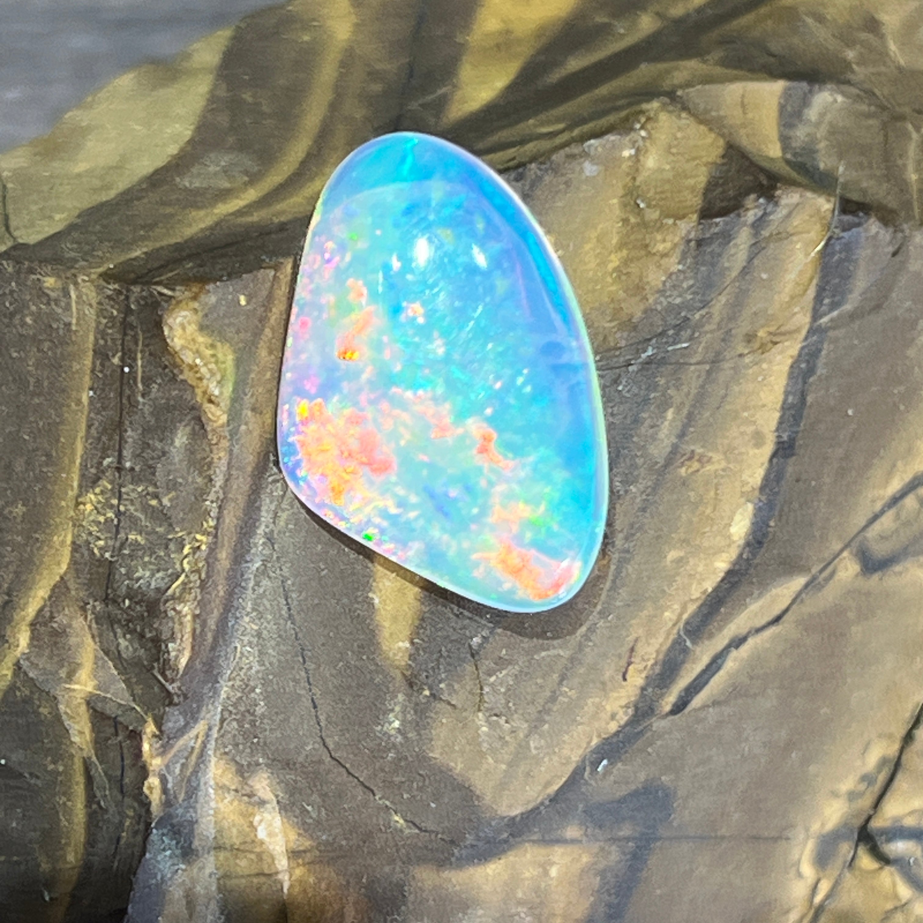 Australian crystal opal, 3.1ct freeform, face up on ironstone with orange and green play of colour