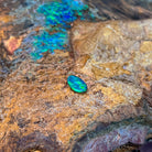 Green fire across a small freeform 0.65ct Australian opal doublet on weathered ironstone