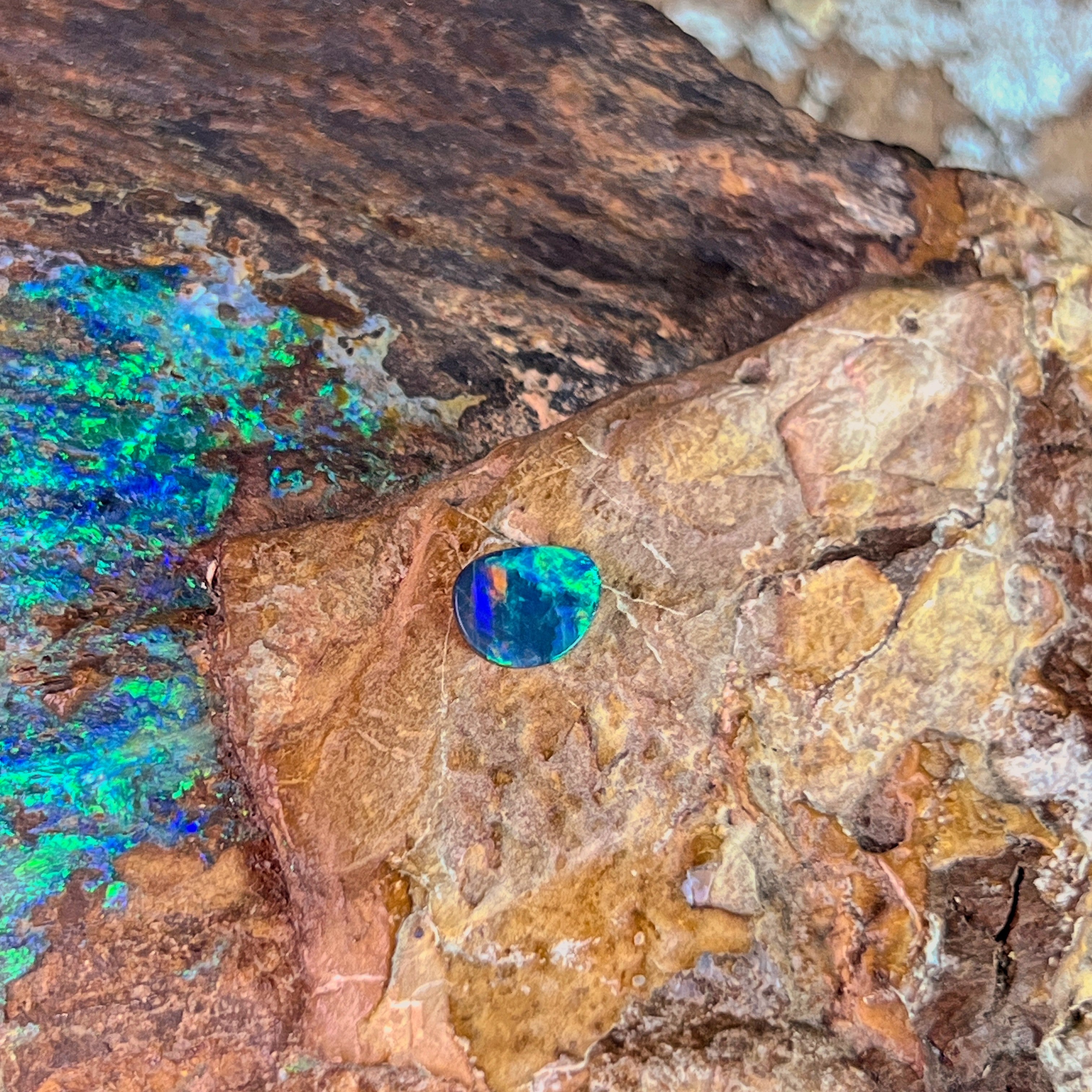 Green and amber sparks in a 0.65ct Australian opal doublet, 7.2x5.7mm, on weathered rock