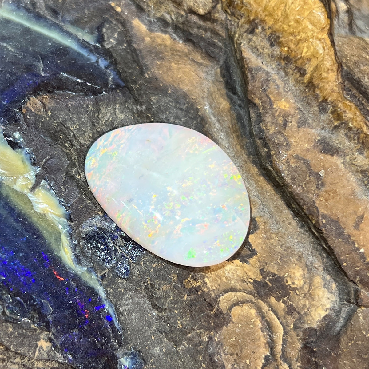 Solid Australian white opal 14.70ct, freeform 28x19.4mm, yellow, orange and green play-of-colour with white colour zones, loose stone on rock