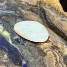 14.70ct freeform white opal loose stone, yellow, orange and green flashes, unset, on rock
