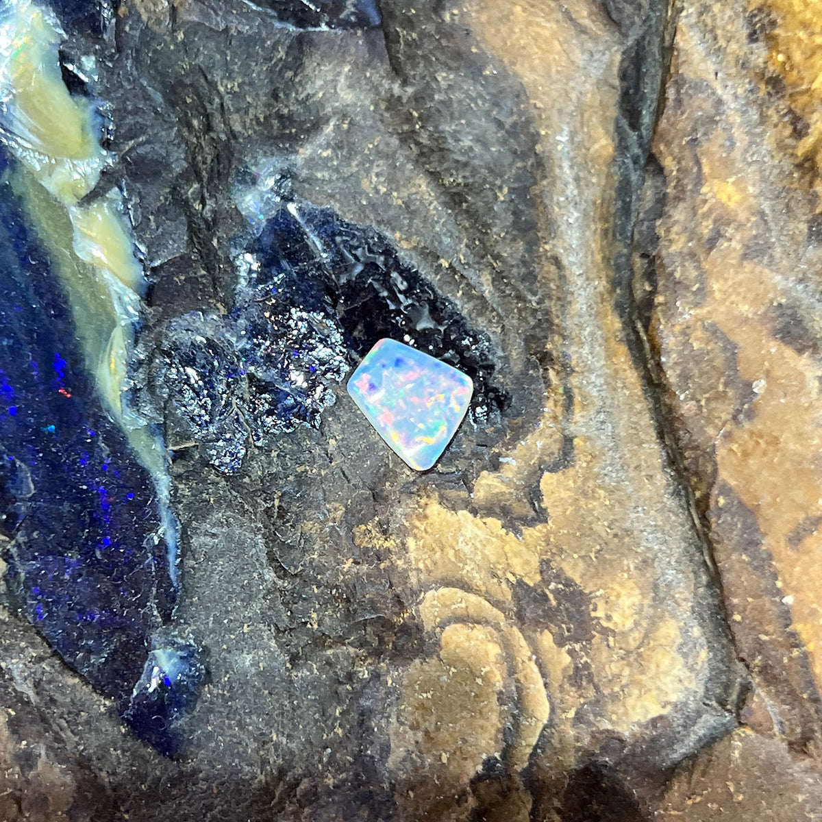 Australian crystal opal 0.65ct freeform cabochon, 7.2x6.8mm, red, orange and green flashes, loose and unset, on rock