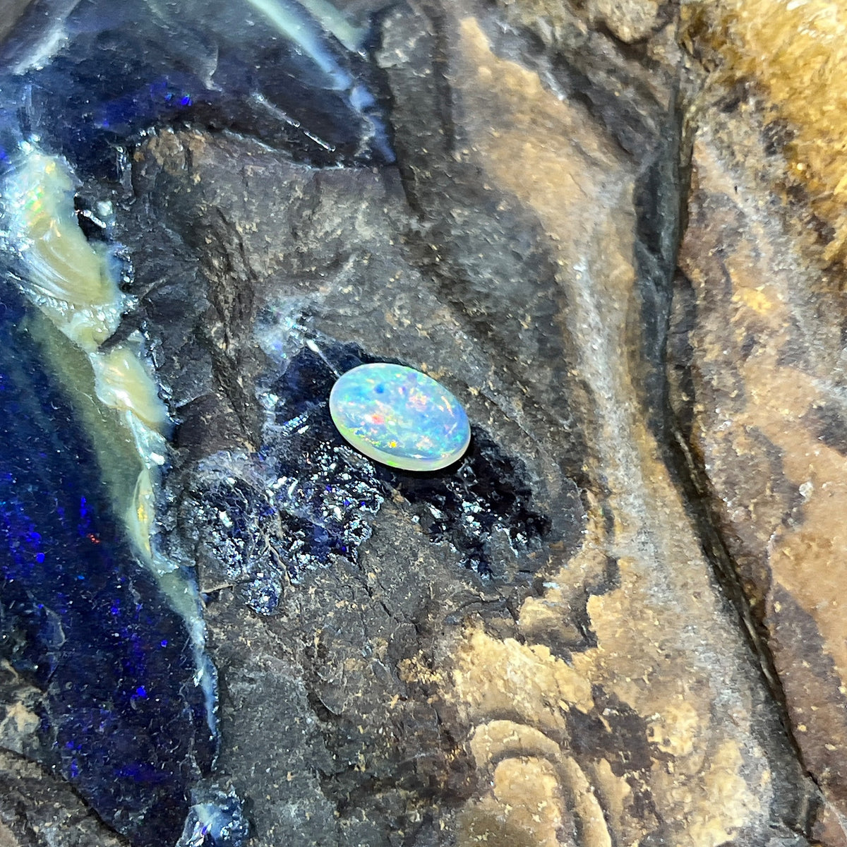 Oval 9x6.8mm solid crystal opal, 1.00ct, red, orange and green flashes across the face, on rock
