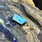 5.15ct rectangular black opal loose stone, yellow, orange, green and blue play-of-colour, unset, on rock
