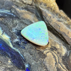 16.50ct triangular crystal opal loose stone, yellow and green play-of-colour with a blue stripe, unset, on rock
