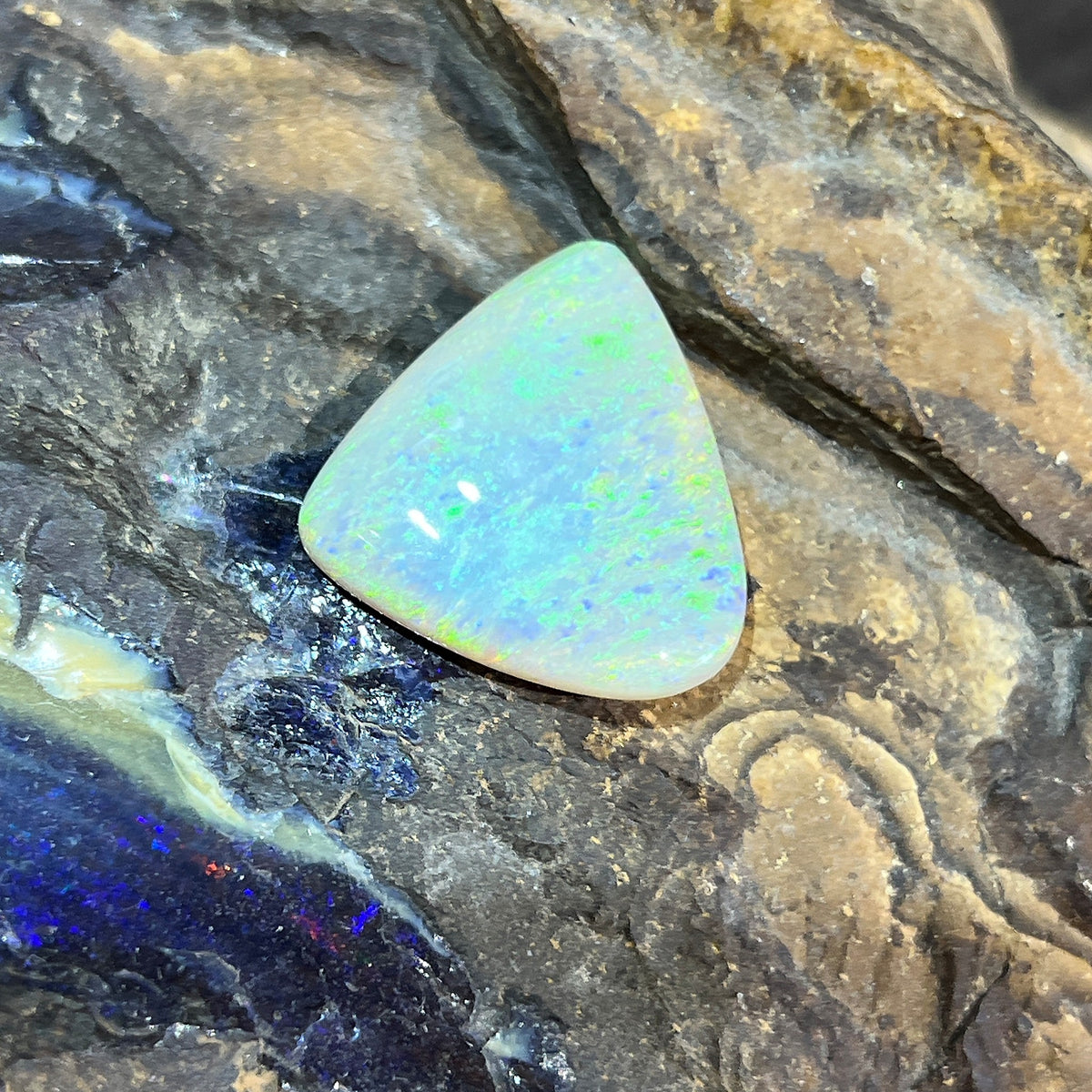 Loose solid crystal opal 16.50ct, triangular, yellow and green with a blue stripe, ready for a custom setting, on rock