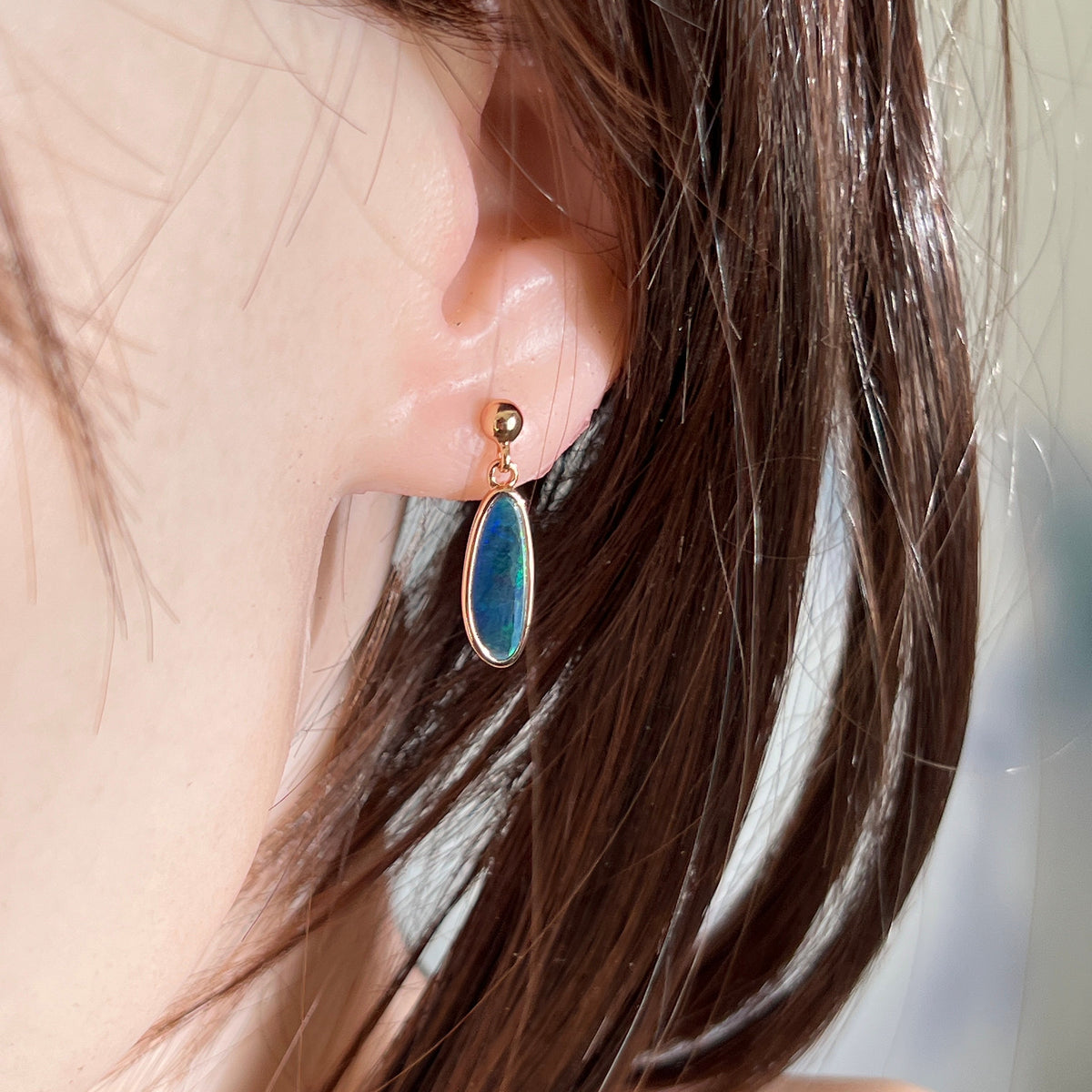 Australian opal doublet earrings worn on the ear, green, blue and yellow play-of-colour