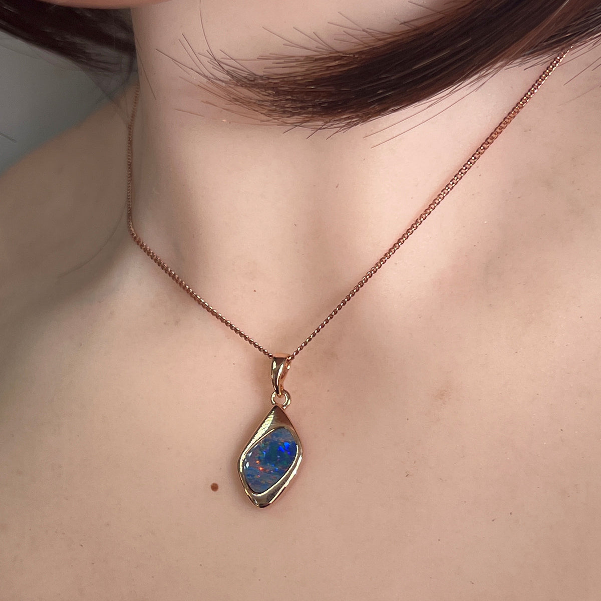 Worn Australian opal doublet pendant in rose gold-plated silver, red, blue and green, 12 x 9mm