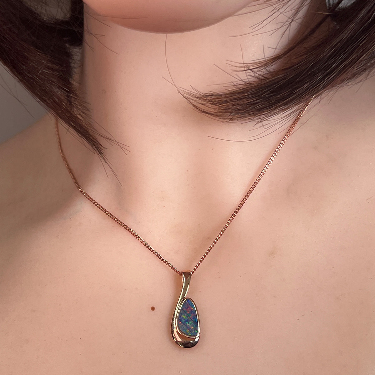Worn Australian opal doublet pendant in rose gold-plated silver, red, blue and green, 12 x 7mm