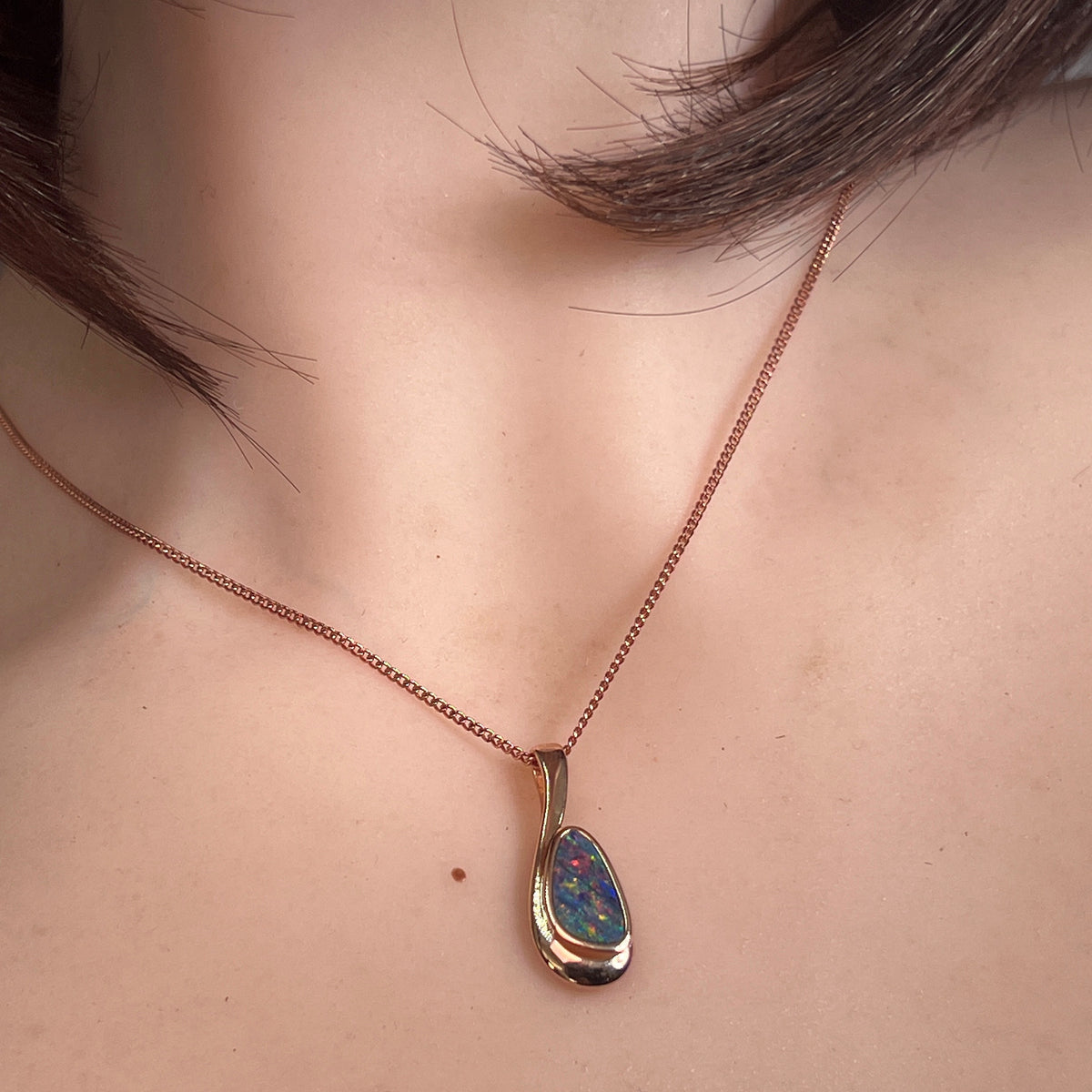 freeform Australian opal doublet pendant worn, rose gold-plated silver, red, blue and green
